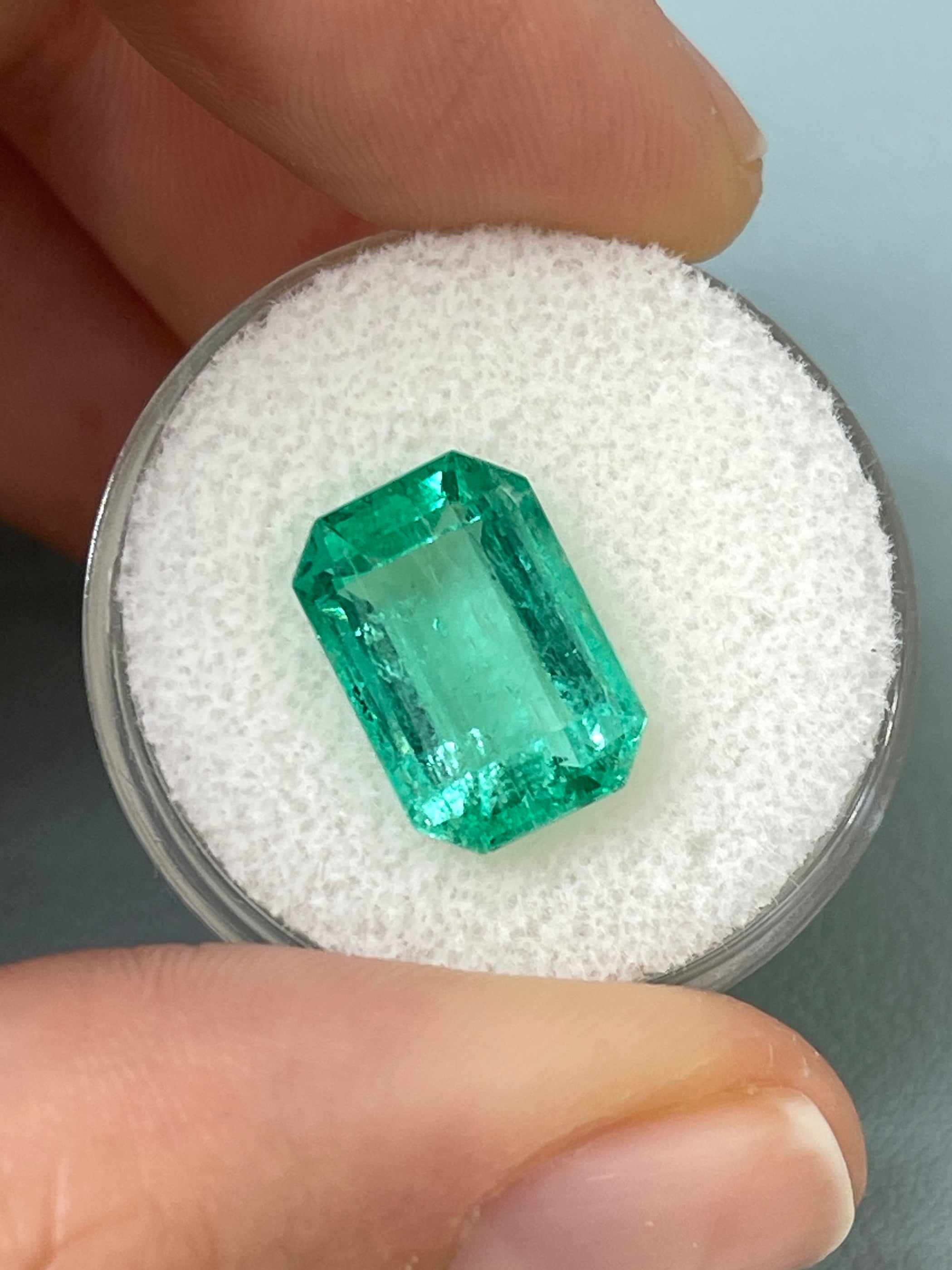 Bluish green 5.45 carat natural loose emerald cut gemstone from JR Colombian Emeralds, showing clarity and vibrant color.
