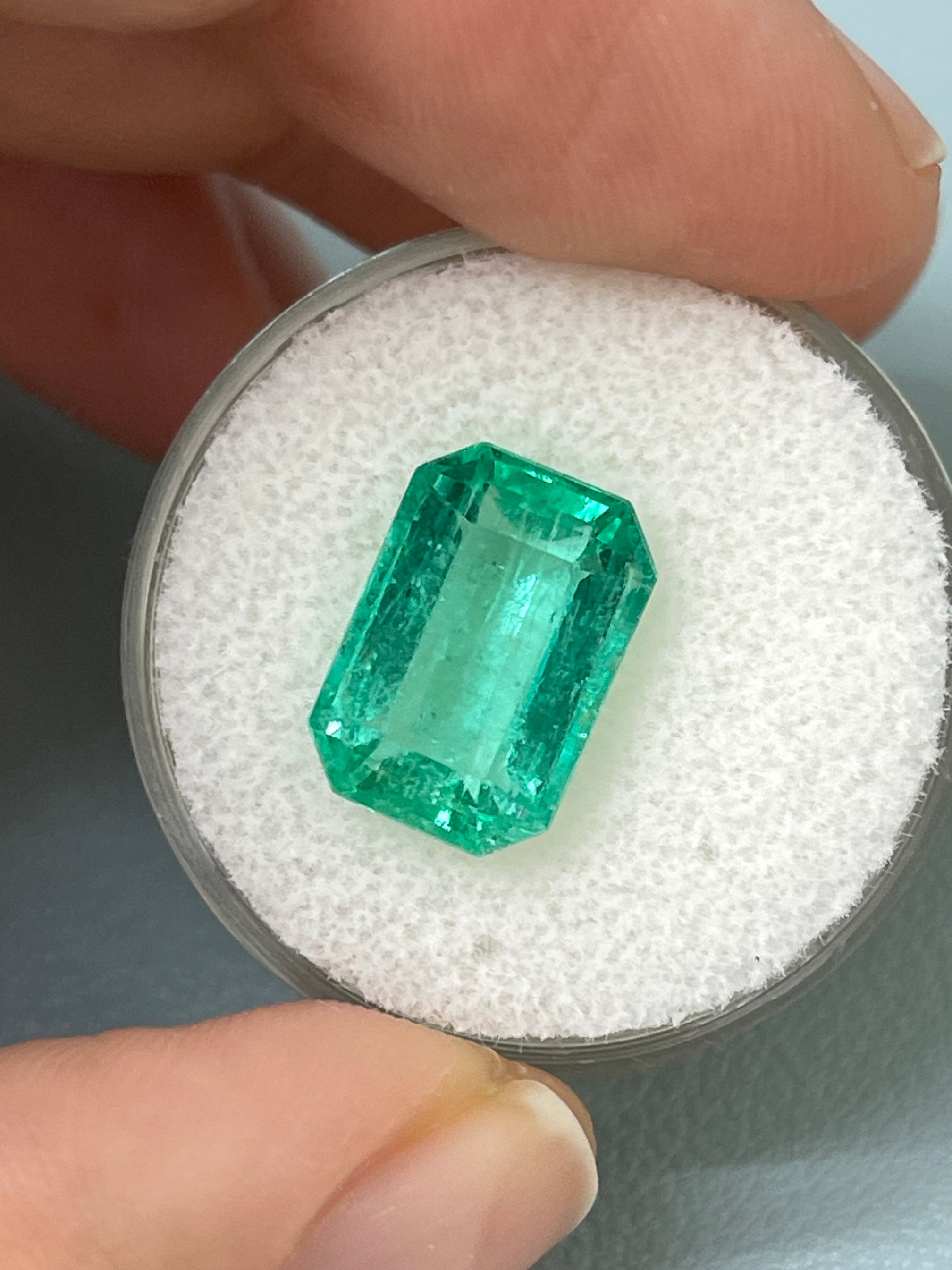 5.45 carat bluish green natural loose emerald cut gemstone from JR Colombian Emeralds, showing its size and clarity.