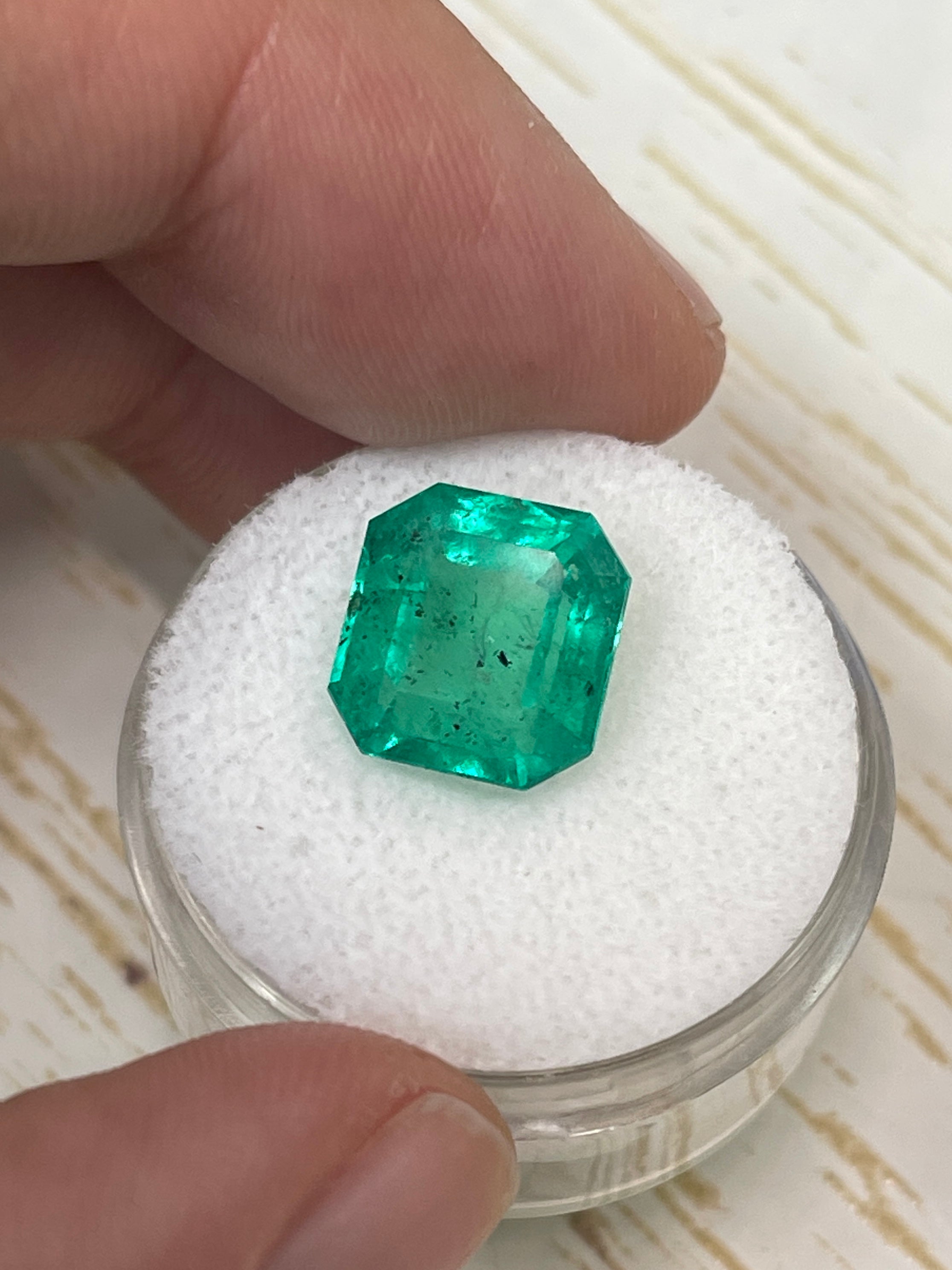 Loose 5.72 carat Colombian emerald in 11x10.5mm Asscher cut with natural freckles, from JR Colombian Emeralds.