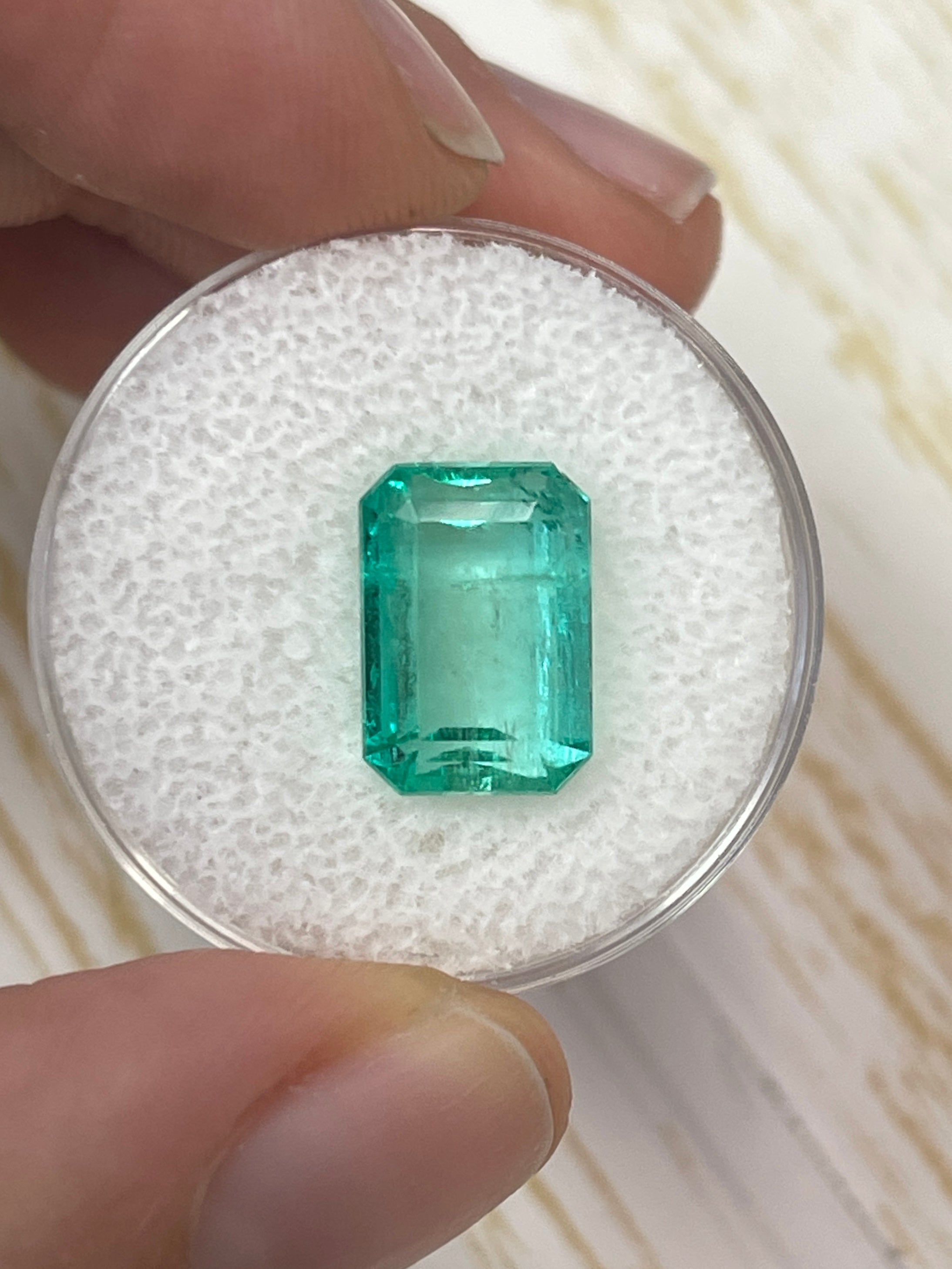5.76-carat clear green natural Colombian emerald loose gemstone in emerald cut, shown on a white background.