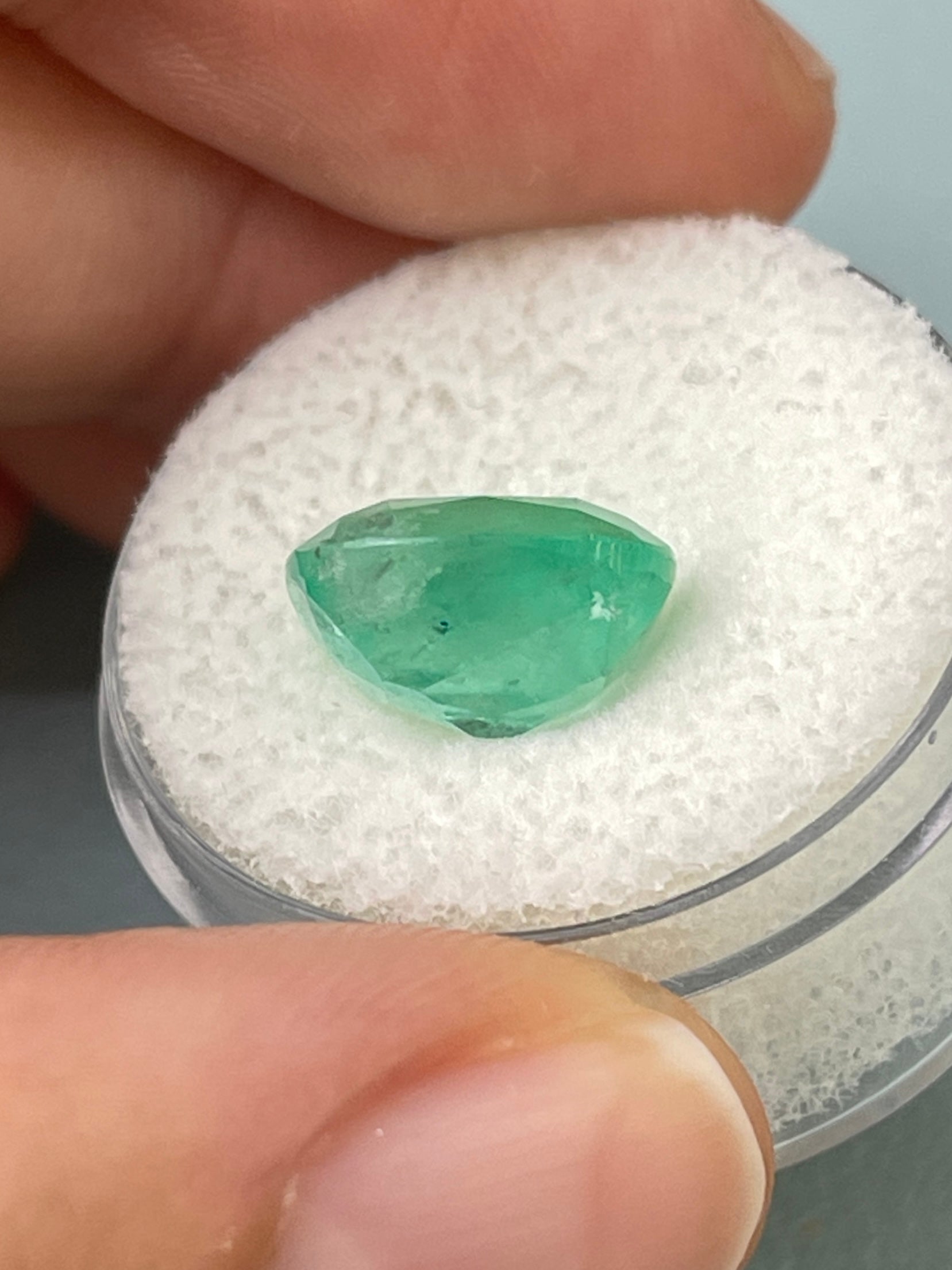 Natural 5.86 carat cushion cut Colombian emerald from JR Colombian Emeralds, earthy pastel green loose gemstone.