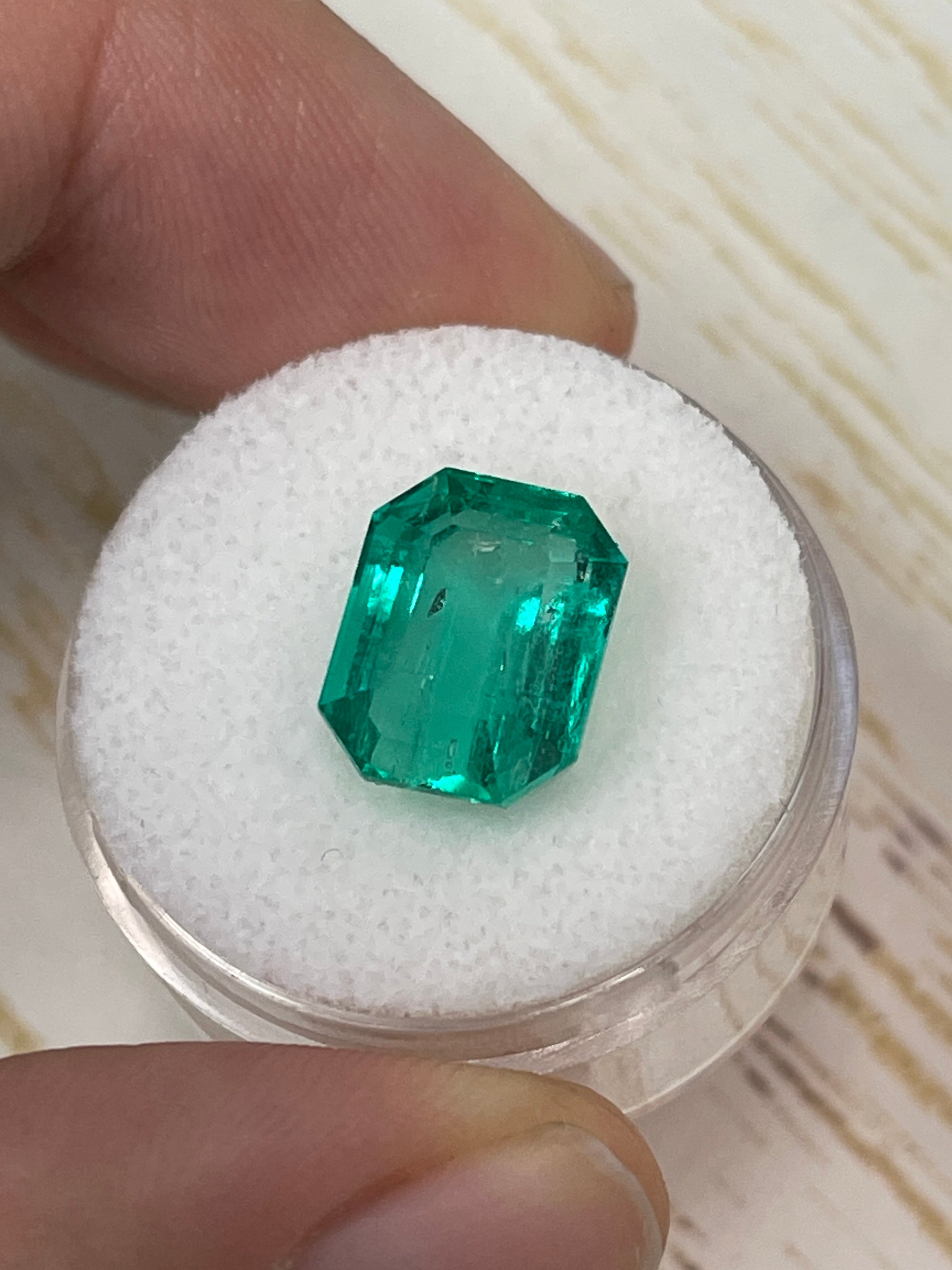 7.06 carat bluish green Colombian emerald loose stone in emerald cut, glowing and vibrant, from JR Colombian Emeralds.