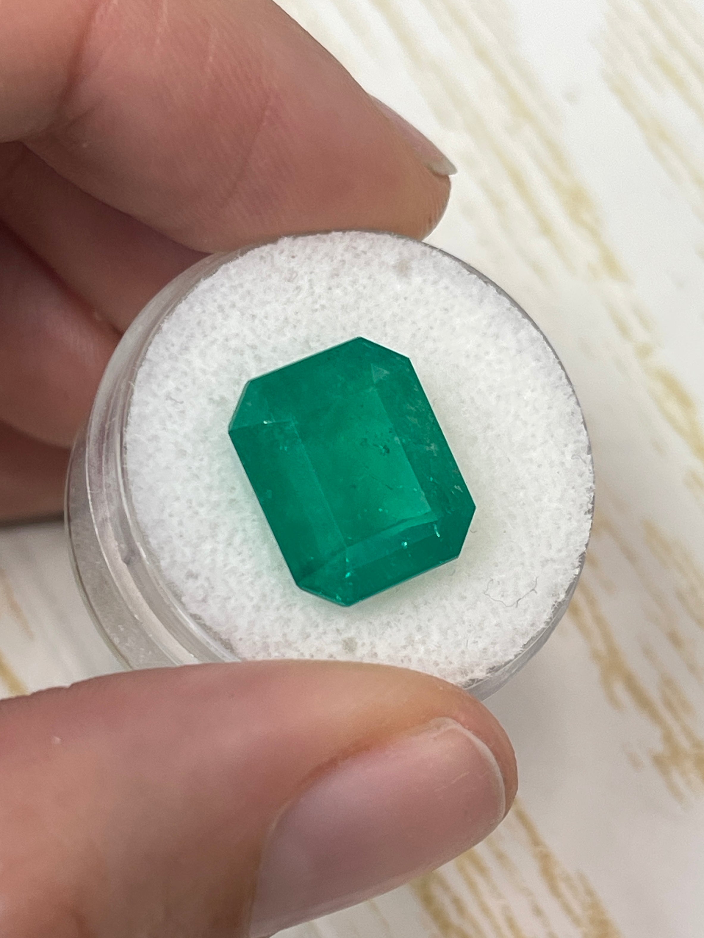Deep forest green 7.51 carat Colombian emerald cut loose gemstone with vivid color and clarity, showcasing its rectangular shape.