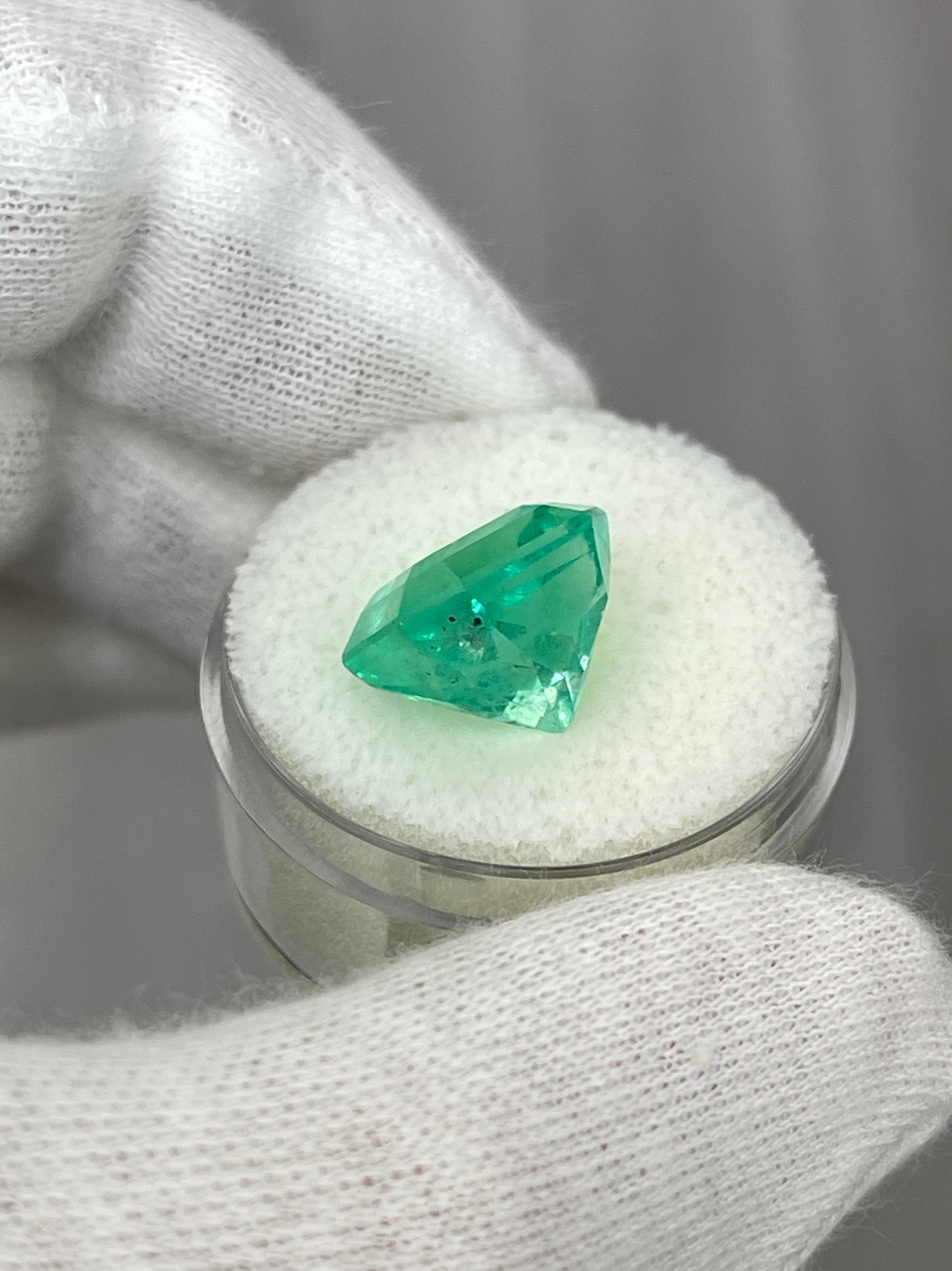 7.76 carat yellowish-green natural Colombian emerald loose gemstone with Asscher cut, displayed against a neutral background.