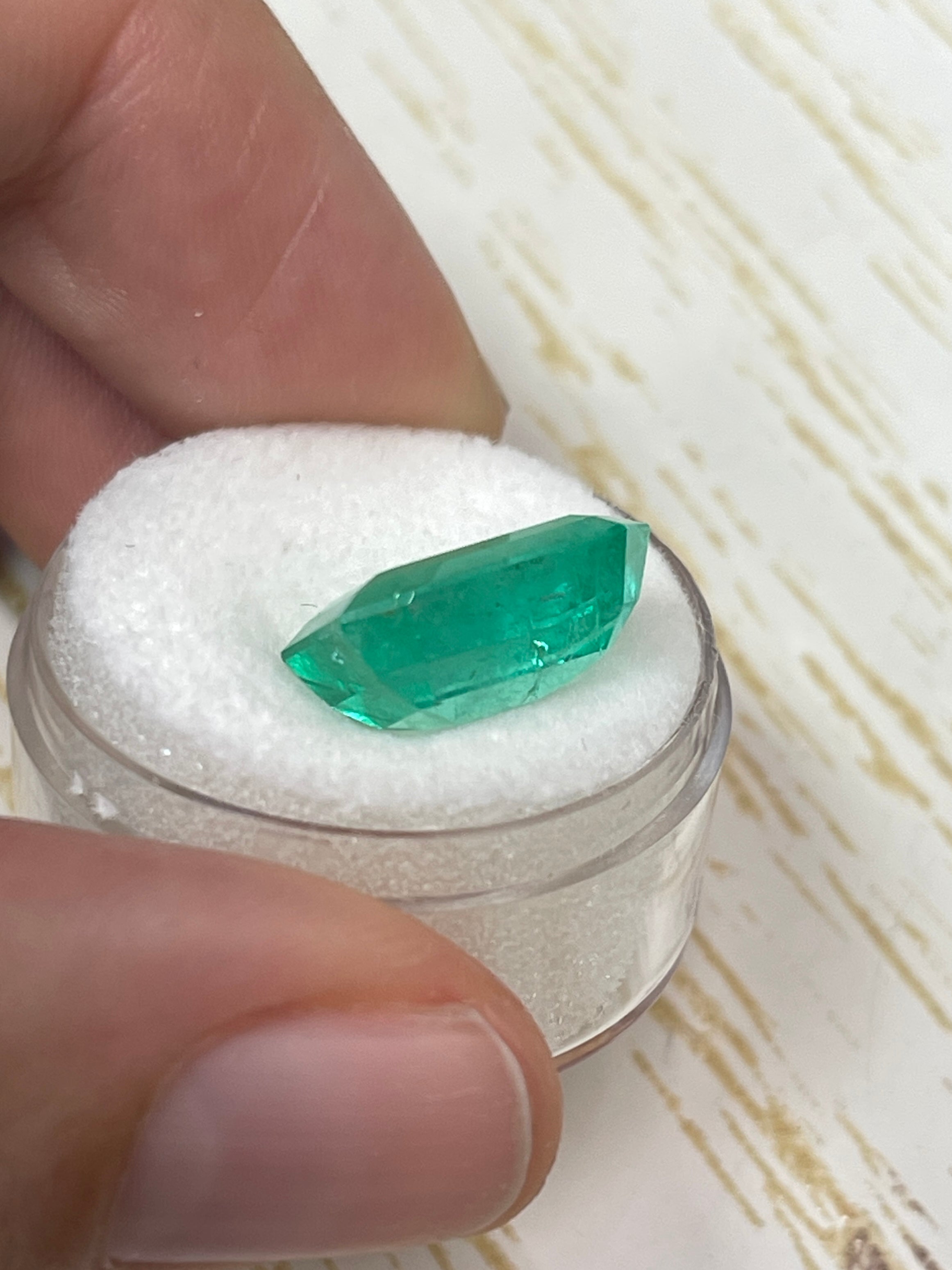 Medium green 8.20 carat Colombian emerald cut loose gemstone with a 14x11.4mm size, showcasing vibrant color and clarity.