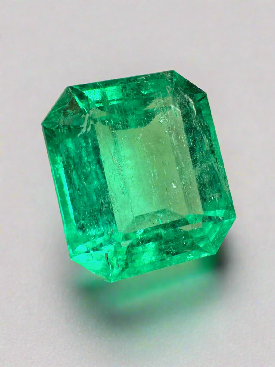 8.33 carat crystal clear Colombian emerald cut loose gemstone with emerald green hue, showcasing a sharp rectangular shape and faceted surface.