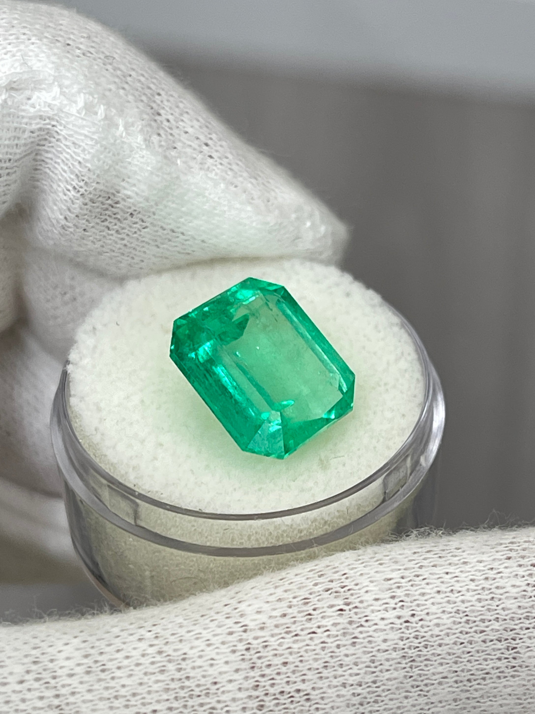 8.33 carat crystal clear Colombian emerald cut loose gemstone with 13x11.5mm dimensions, displayed against a neutral background.