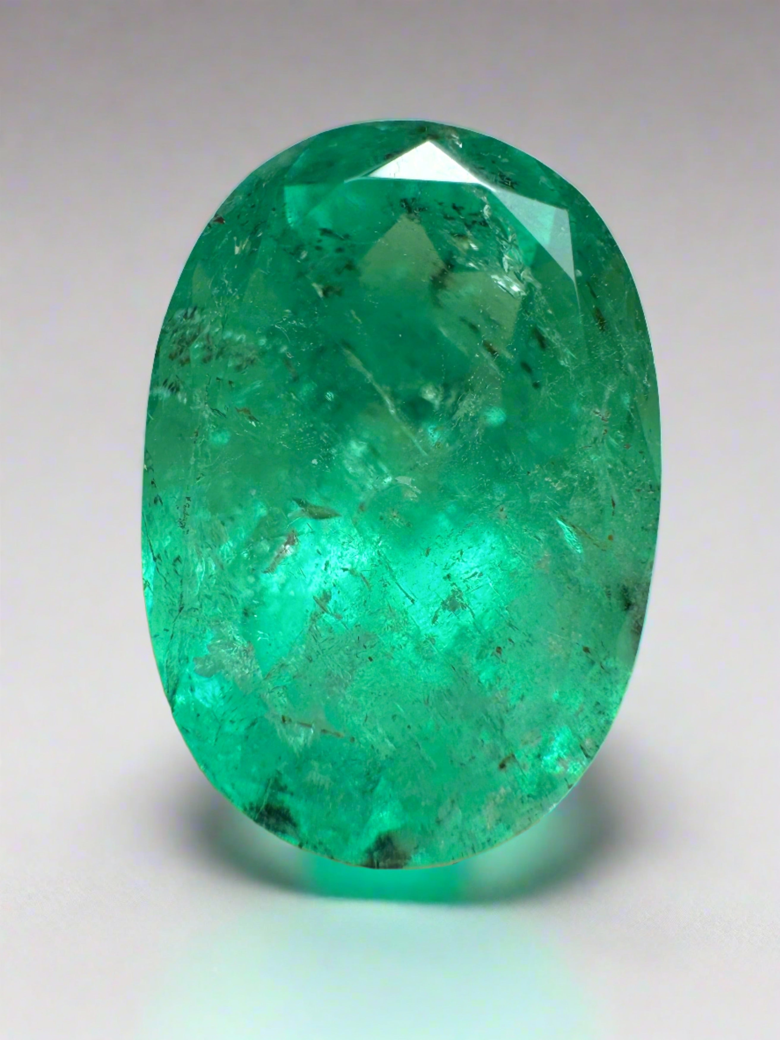8.64 carat freckled medium green Colombian emerald in oval cut, natural loose gemstone from JR Colombian Emeralds.