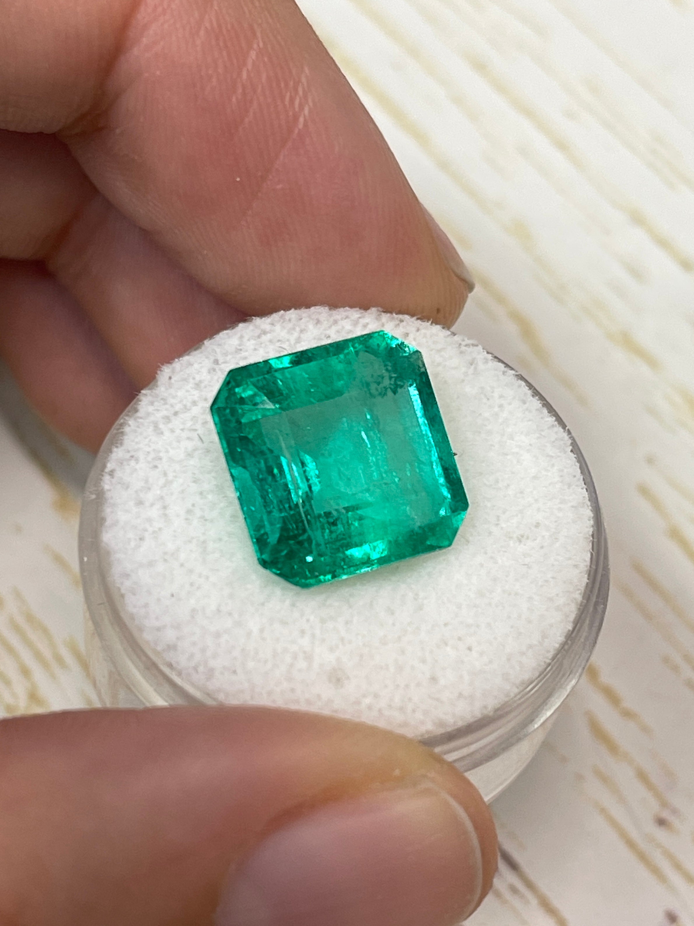8.81 carat glowing green natural Colombian emerald loose gemstone with Asscher cut, displayed against a neutral background.