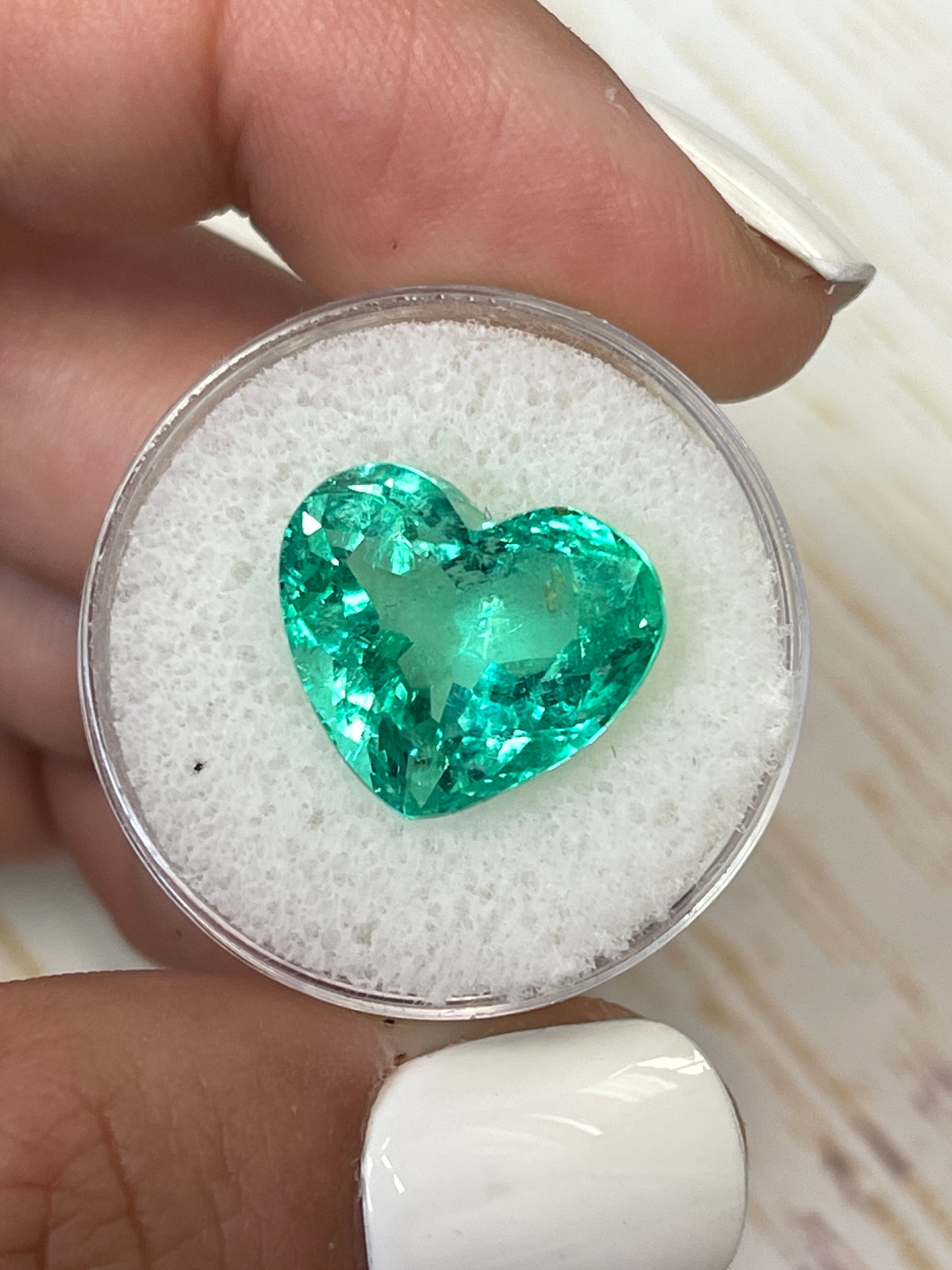 9.86 carat yellowish green natural Colombian emerald loose gemstone in heart cut, showcasing vibrant color and clarity.