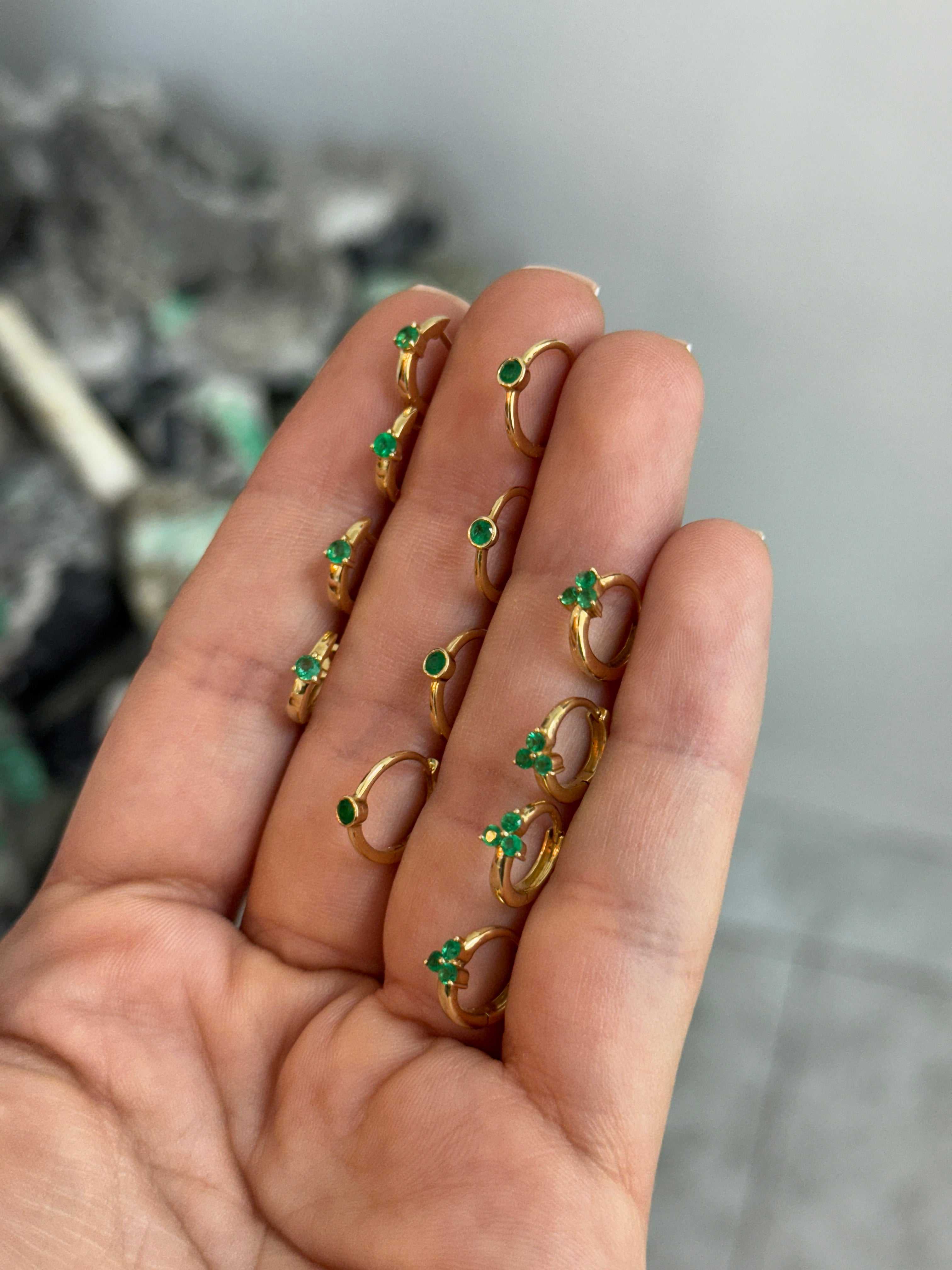 Emerald Huggie Earring by JR Colombian Emeralds featuring three-prong 14K gold design, close-up of the jewelry piece.