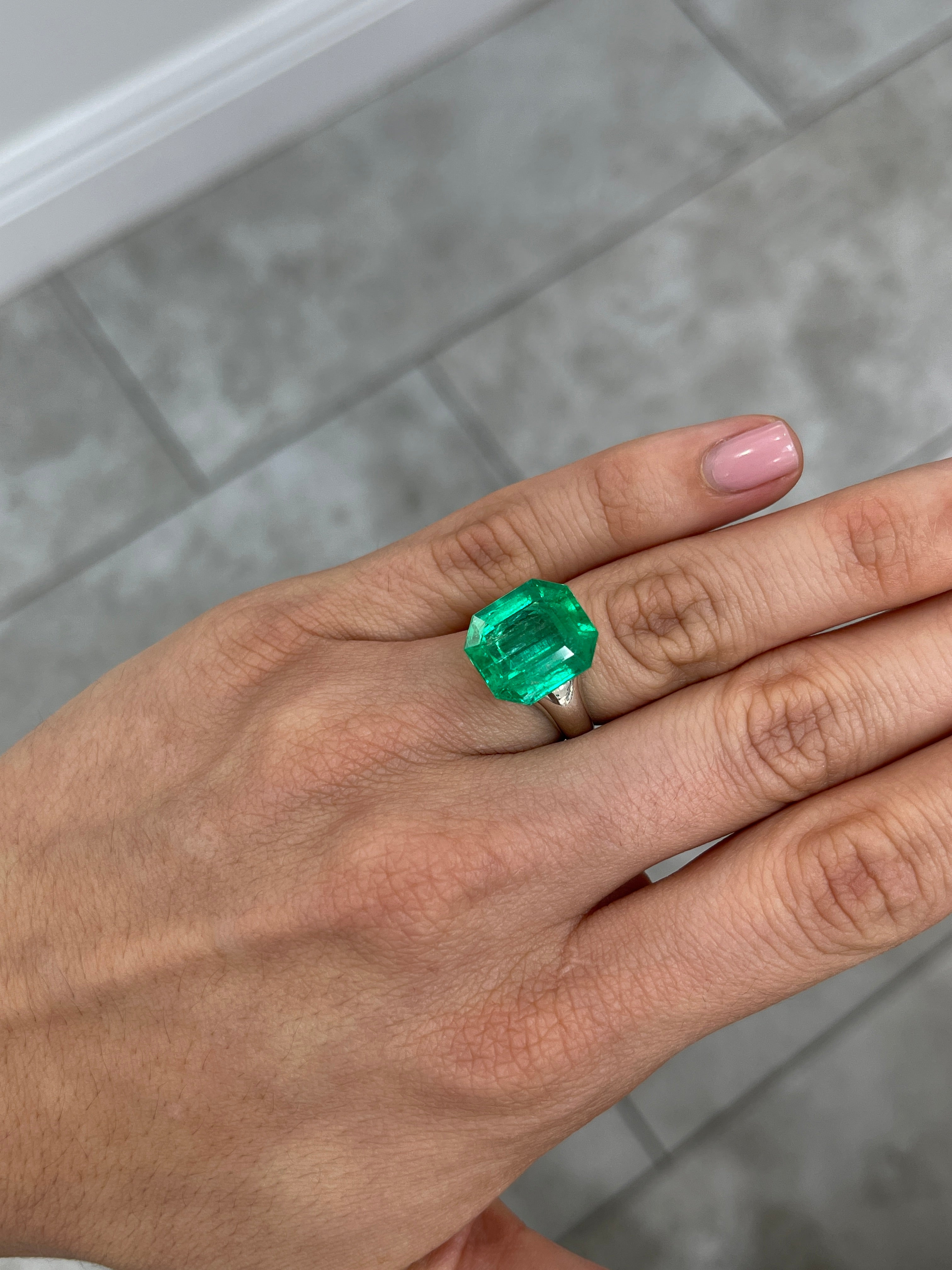 Large 10.97 carat Muzo Colombian emerald cut loose gemstone with deep jungle green color, displayed against a neutral background.
