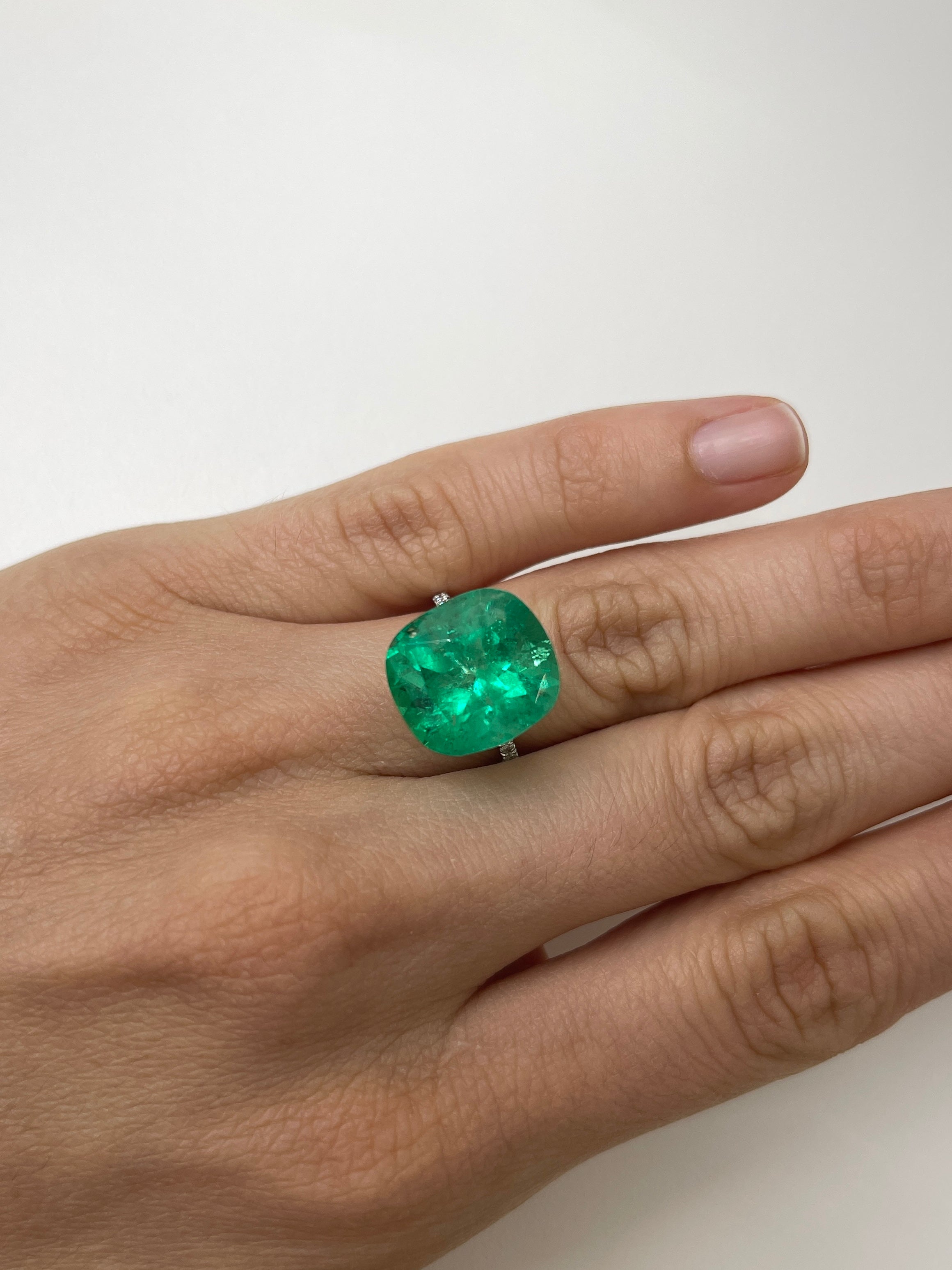 Large 12.27 carat Muzo yellowish green Colombian emerald loose cushion cut gemstone with natural clarity.