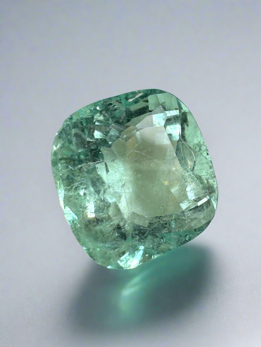 Large 12.86 carat natural cushion-cut Colombian emerald from JR Colombian Emeralds displayed in a close-up image.