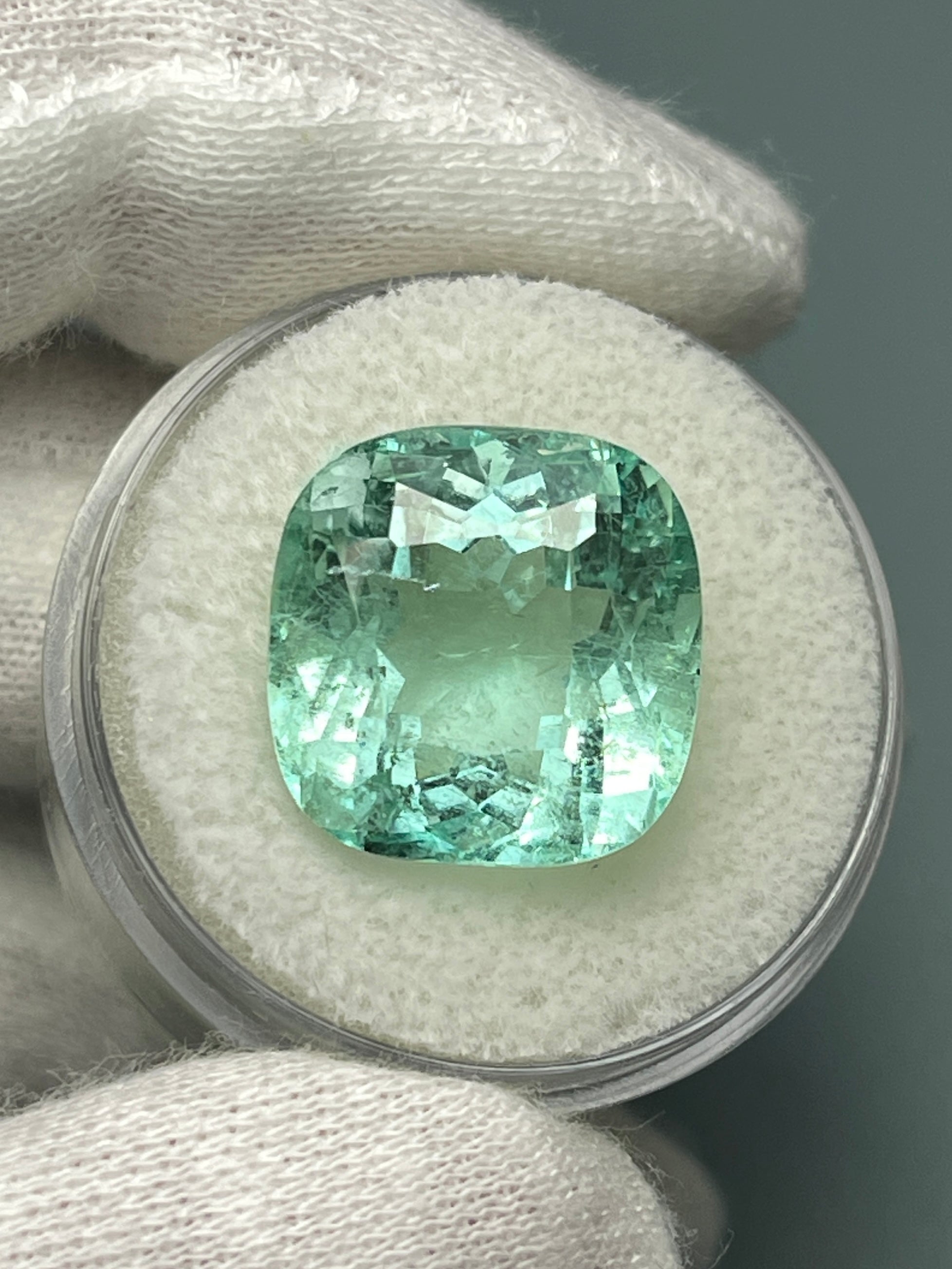 Large 12.86 carat natural cushion-cut Colombian emerald from JR Colombian Emeralds showing vibrant green color and clarity.
