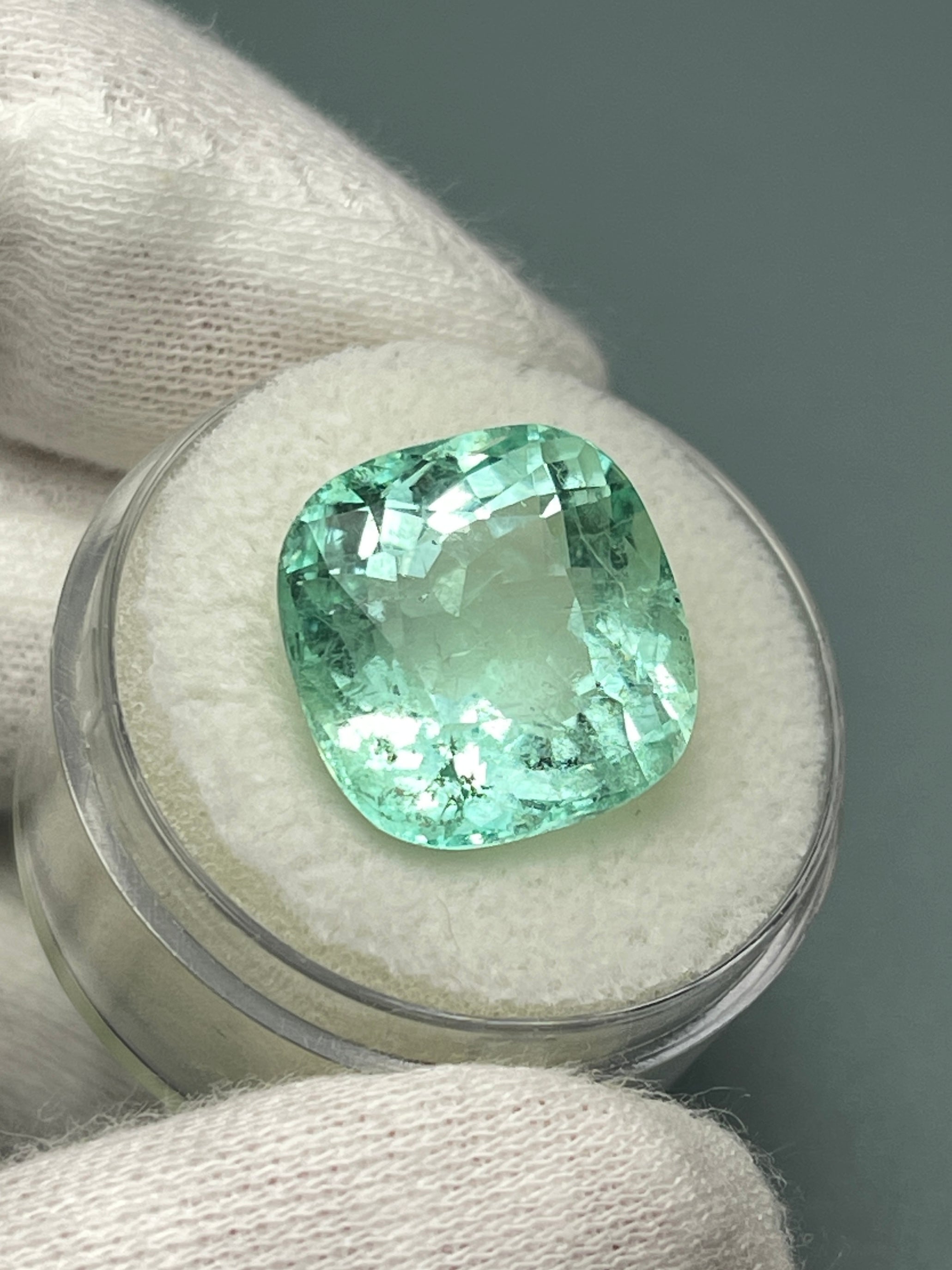 Large 12.86-carat natural cushion-cut Colombian emerald from JR Colombian Emeralds, showcasing vibrant green color and clarity.