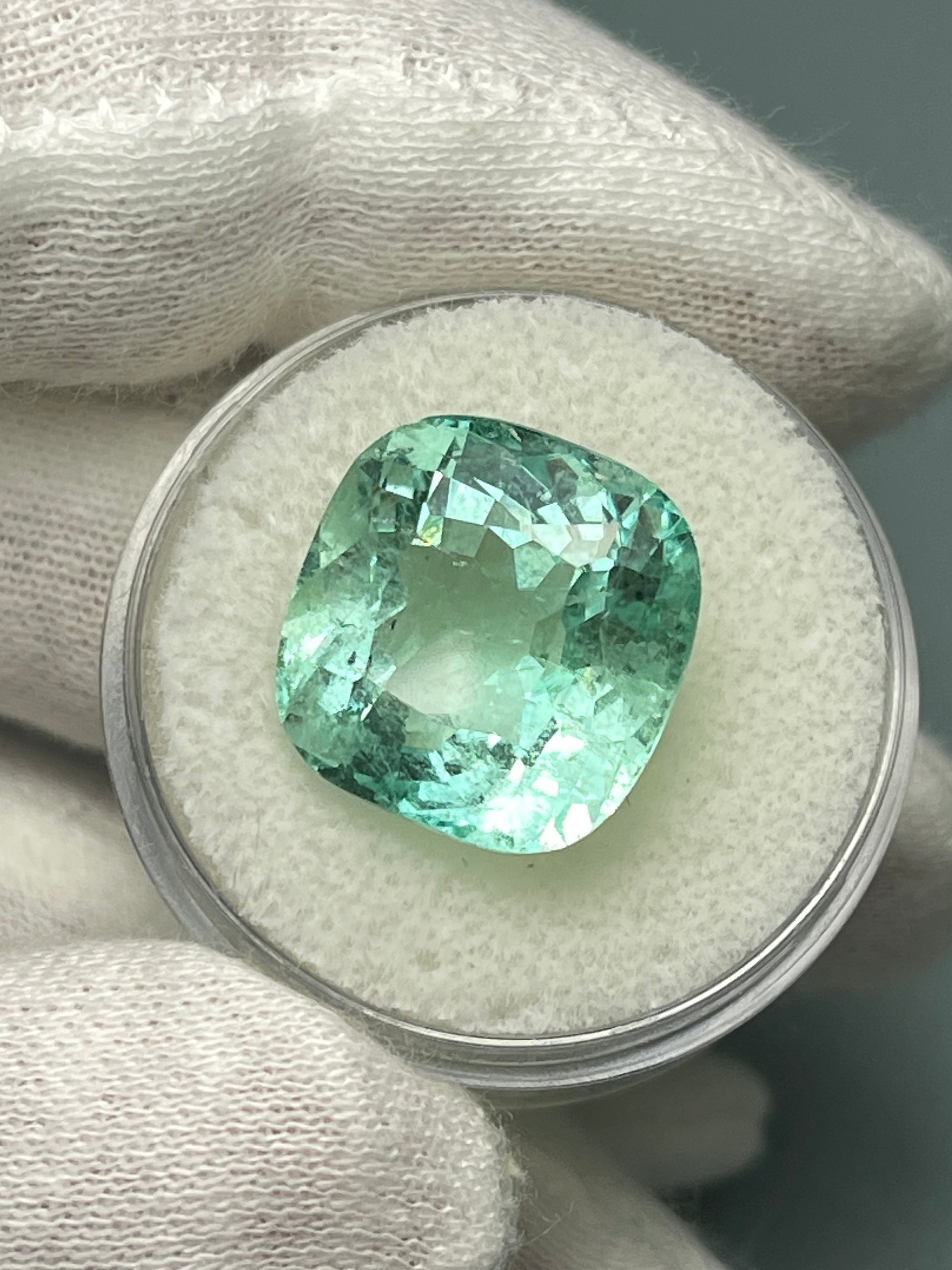 Large 12.86 carat natural cushion-cut Colombian emerald from JR Colombian Emeralds, showcasing vibrant green color and clarity.