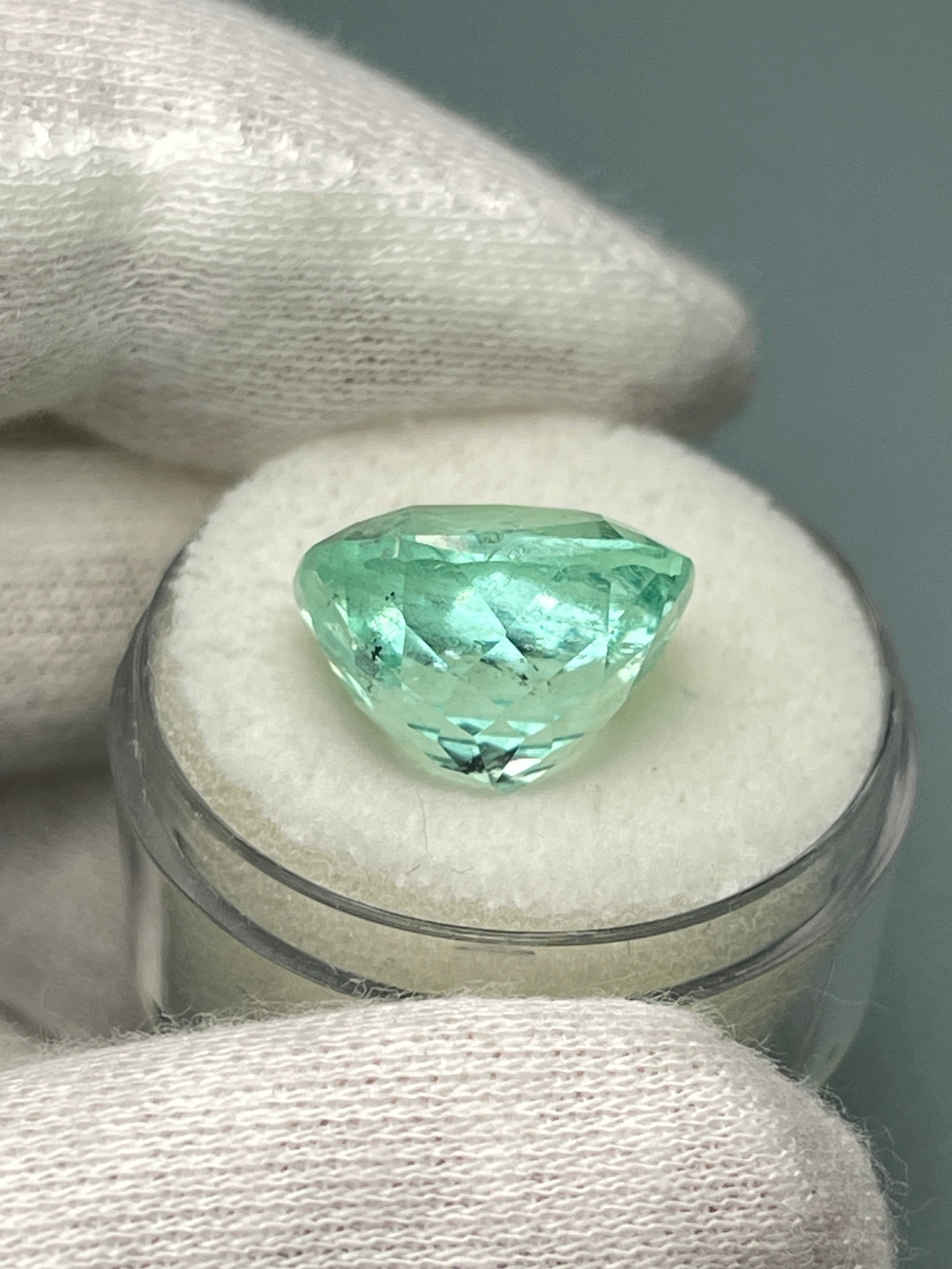 Large 12.86 carat natural cushion-cut Colombian emerald from JR Colombian Emeralds, showcasing vibrant green color and clarity.