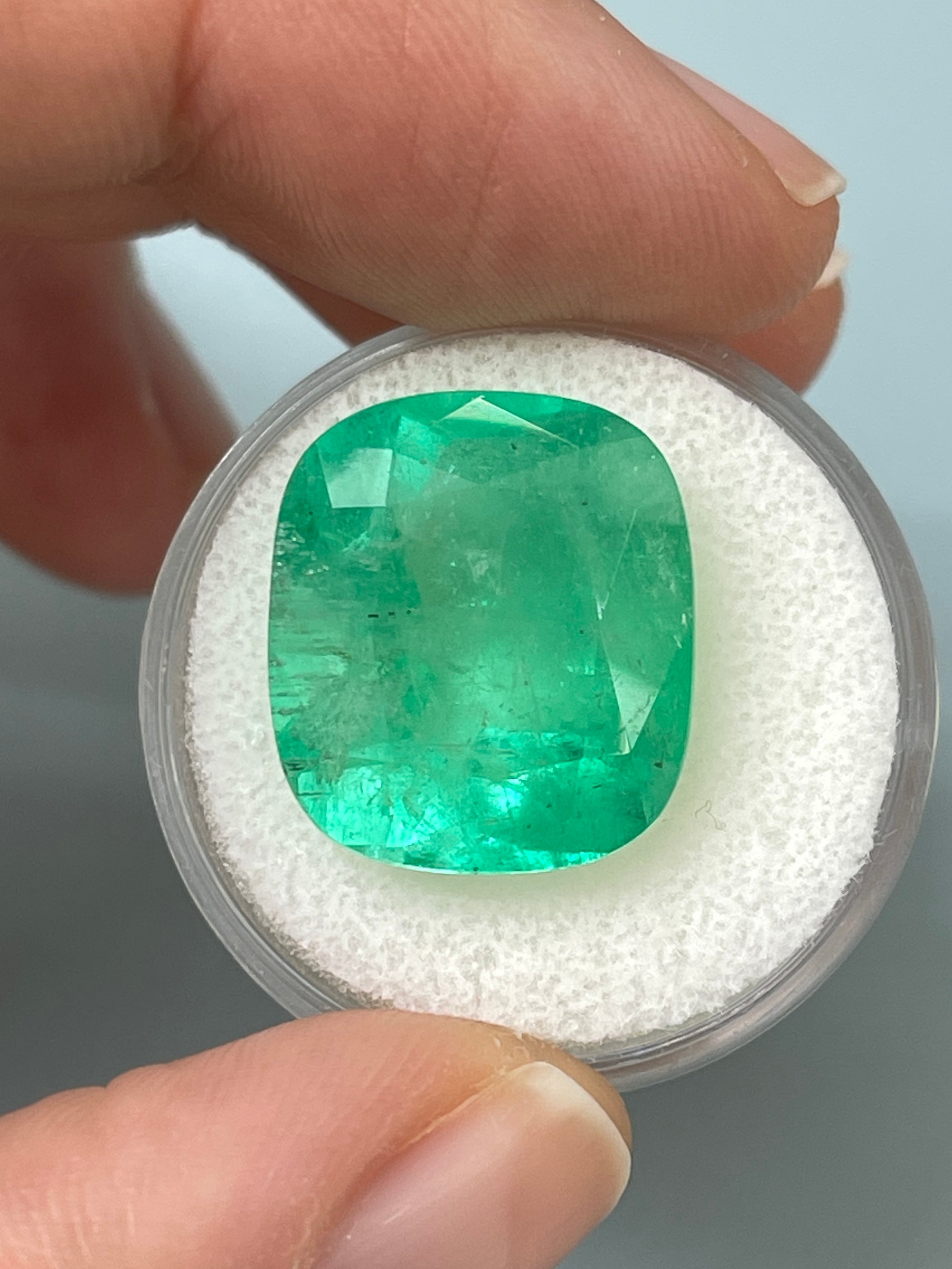 Large 17.5x15 Colombian emerald cushion cut gemstone from JR Colombian Emeralds, showcasing vibrant green color and natural clarity.