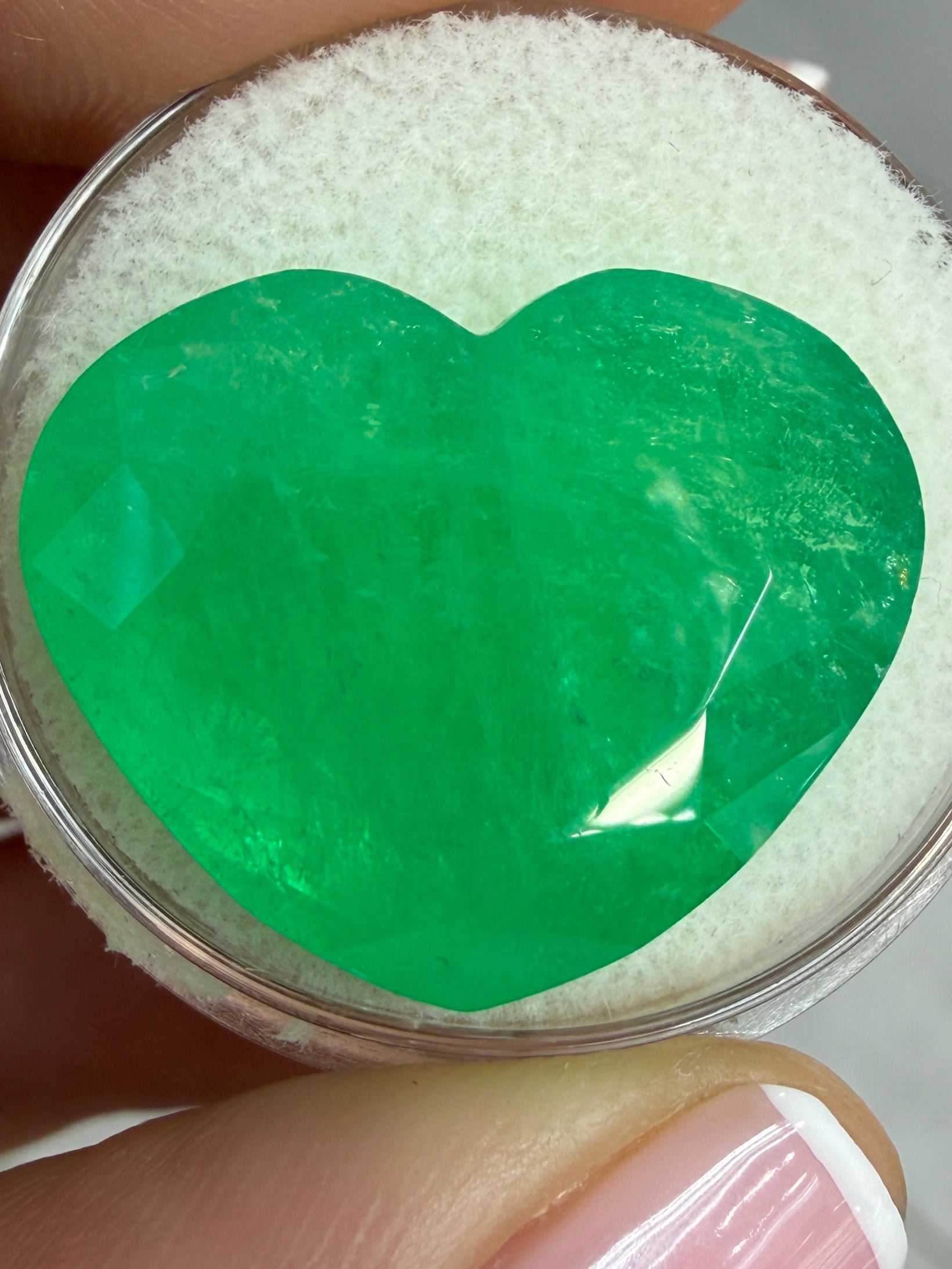 Bright green 23.97 carat natural Colombian emerald in heart cut, loose gemstone displayed by JR Colombian Emeralds.