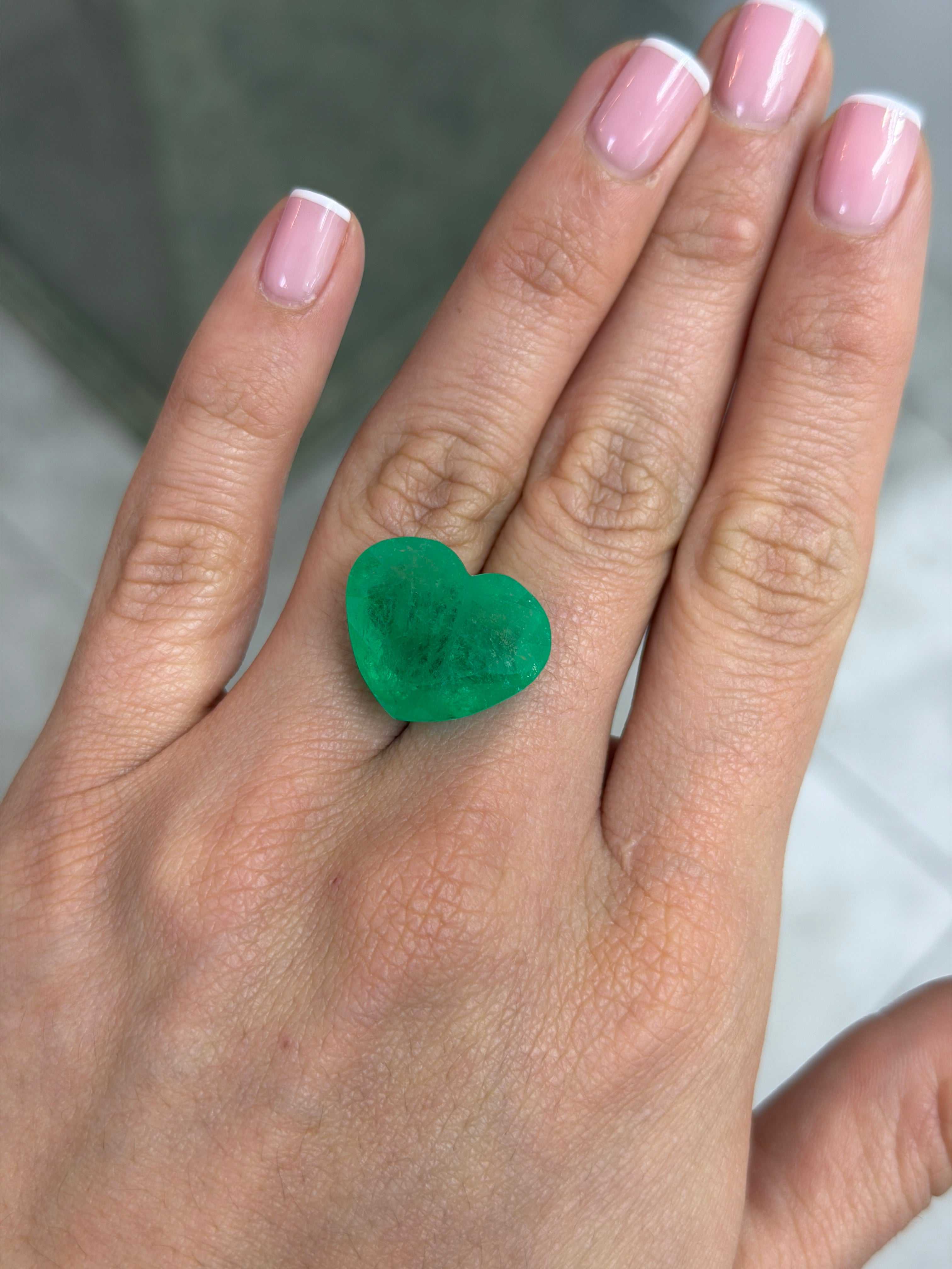Large 23.97-carat bright green natural Colombian emerald in heart cut, loose gemstone, showcasing vibrant color and clarity.