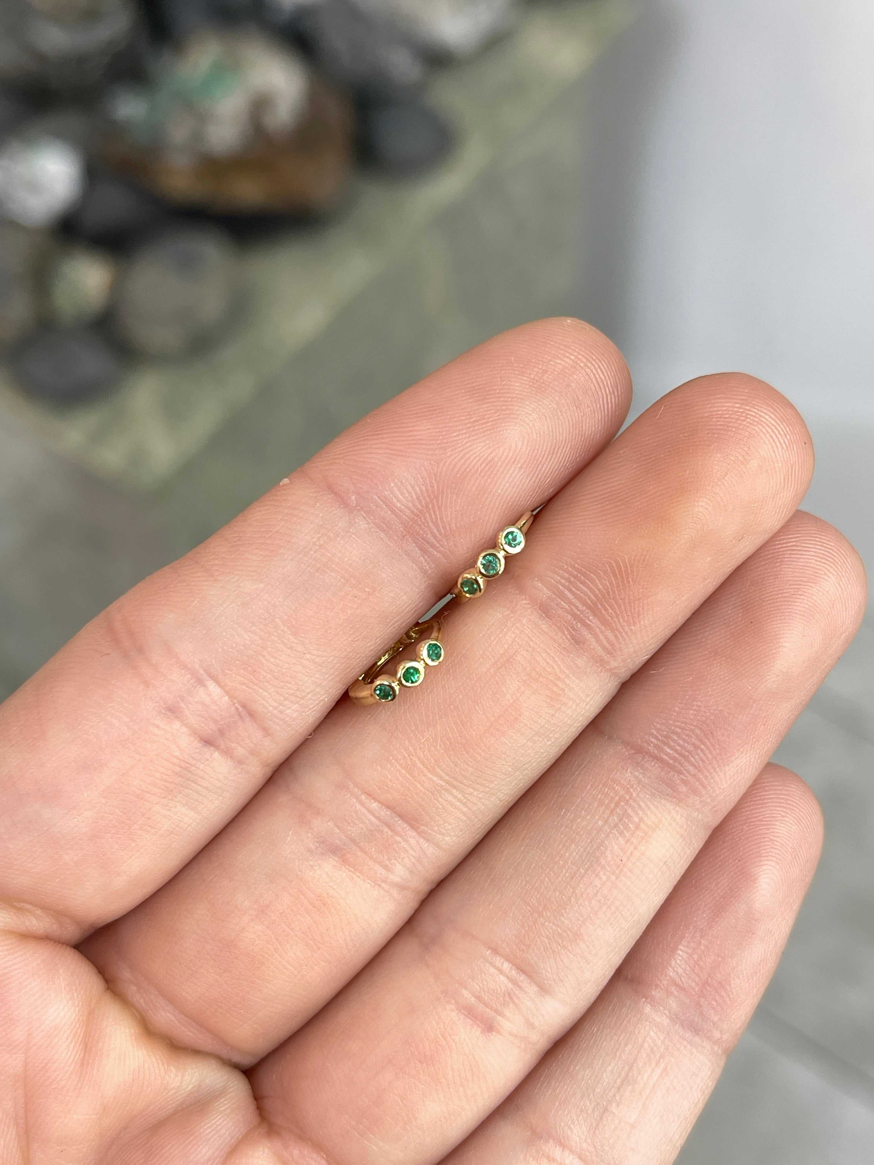 Mini bezel set emerald huggie hoop earrings in 14K gold with round green stones
