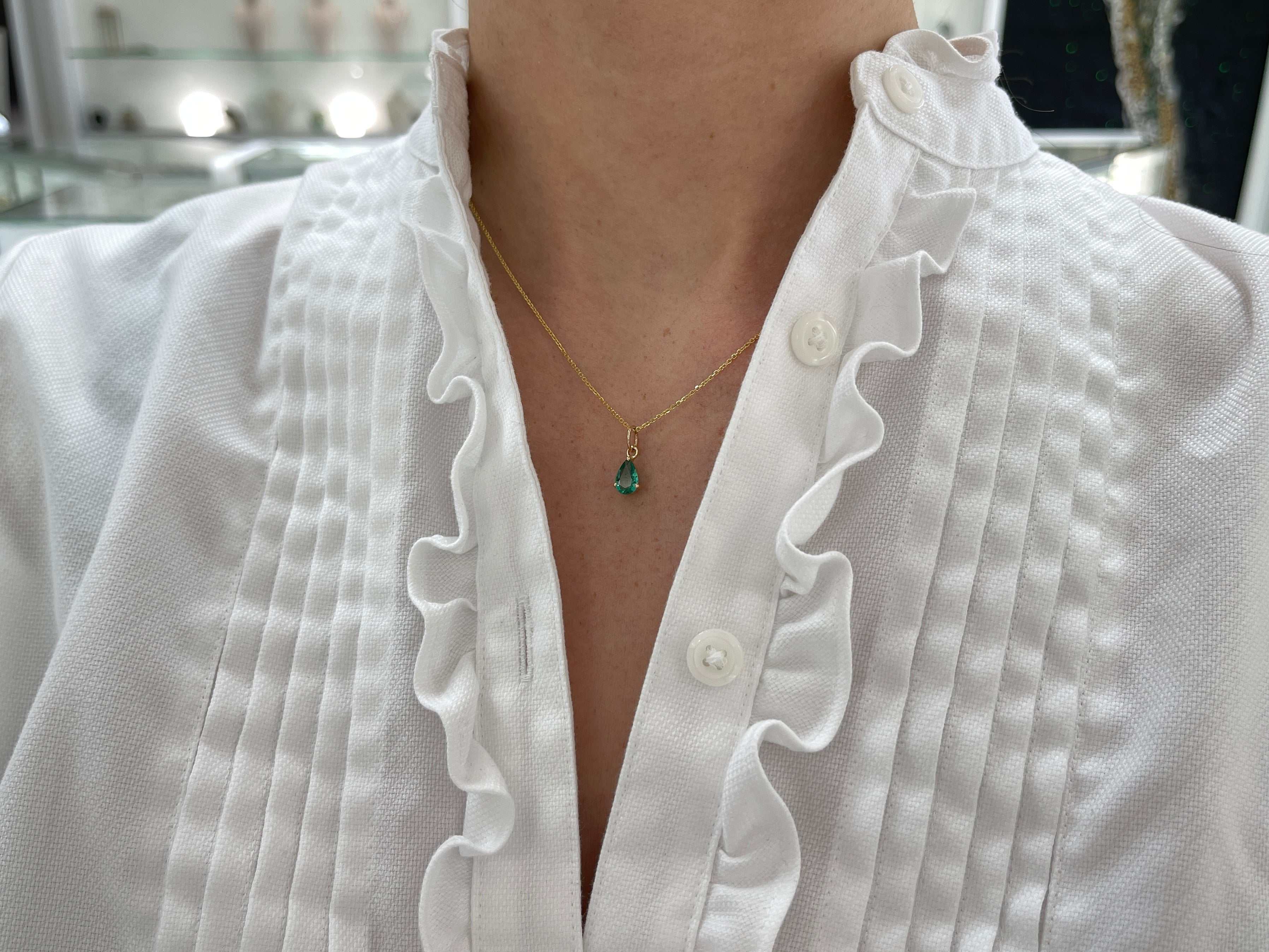 Petite 0.70ct natural freckled teardrop emerald pendant with prong setting in 14K gold by JR Colombian Emeralds.