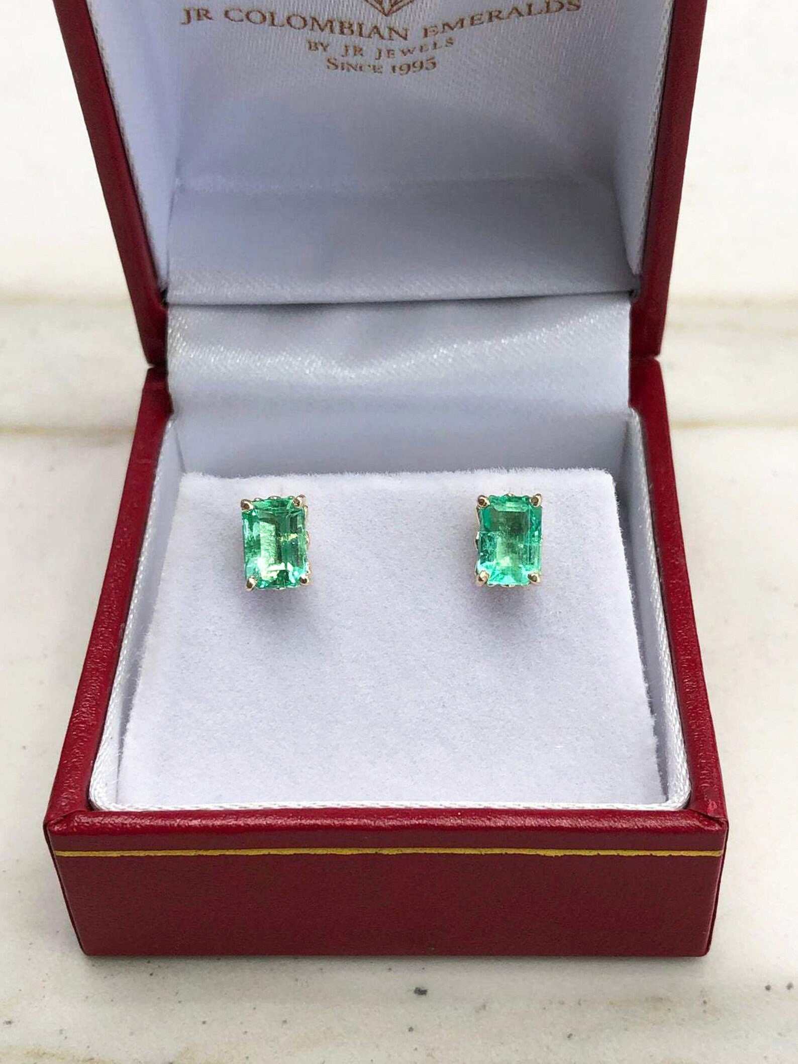 Trendy 1.50tcw Colombian emerald cut stud earrings in 14K gold by JR Colombian Emeralds, featuring elegant fleur de lis design.