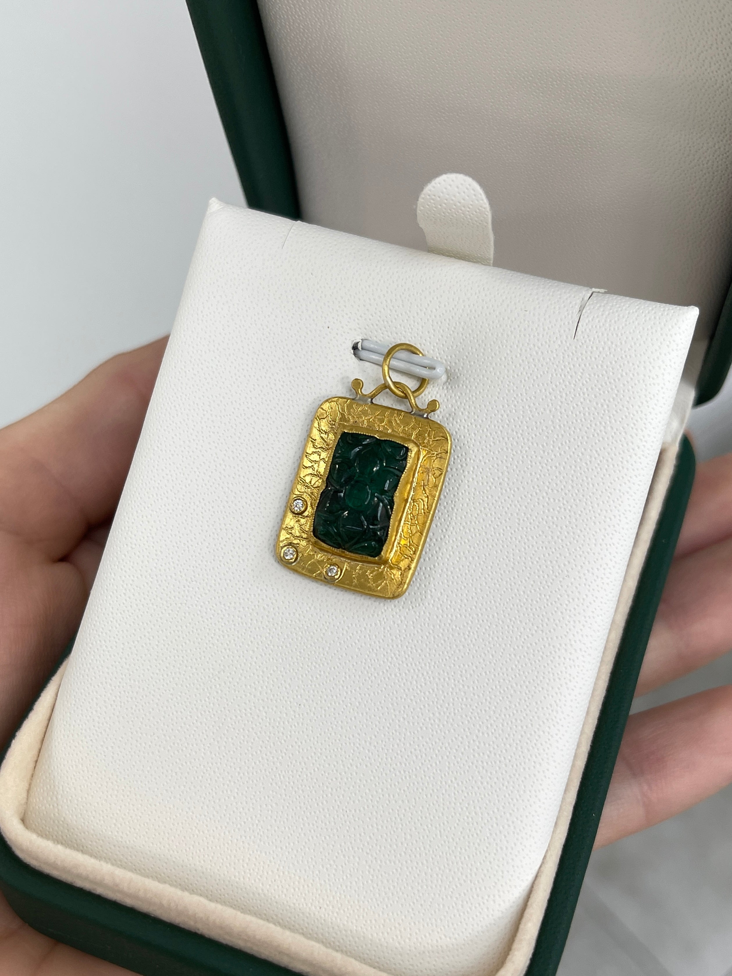 Hand-carved floral emerald and diamond pendant in 24K gold, showcasing intricate detailing and vibrant green hues.