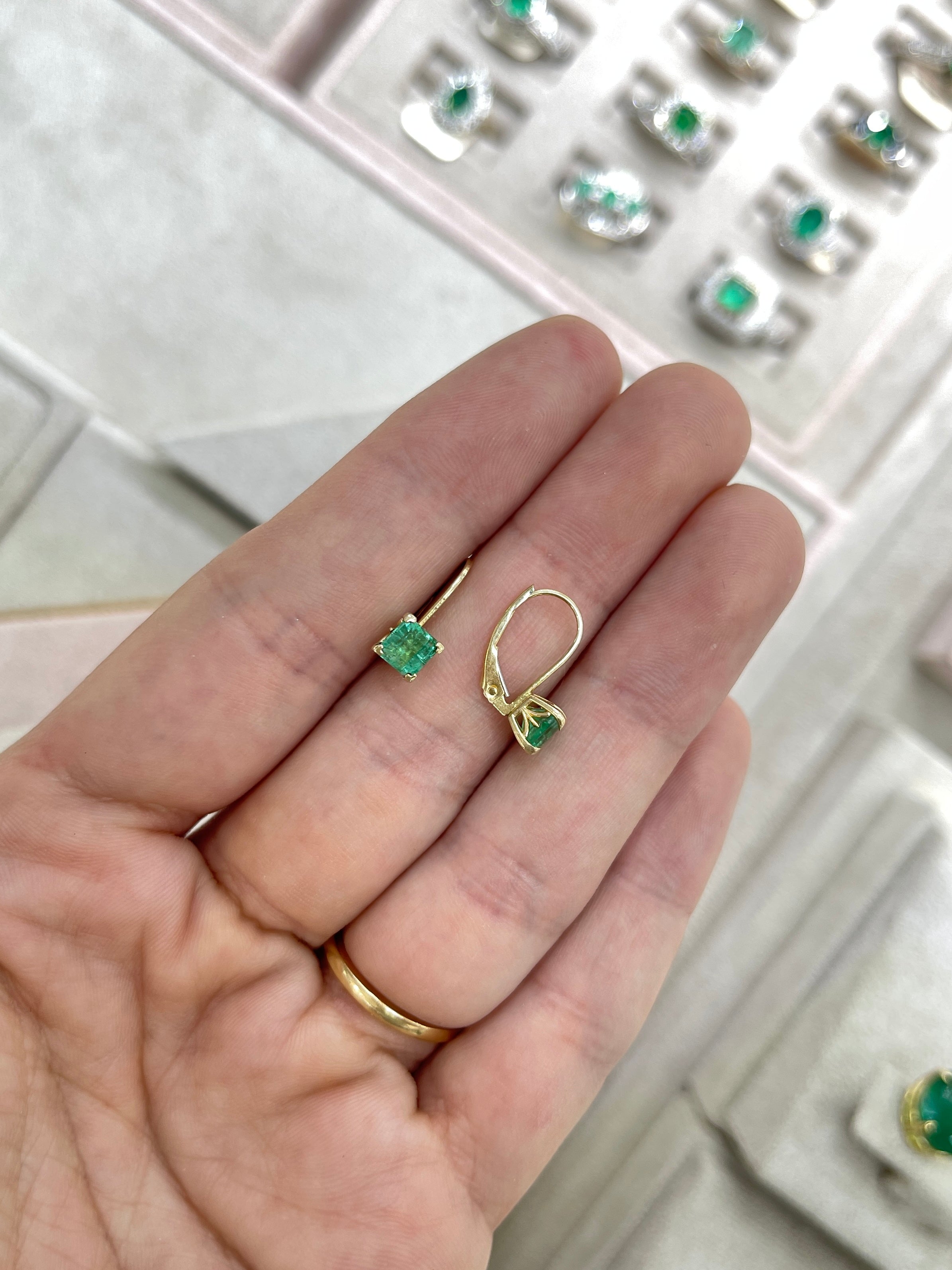 Square emerald leverback earrings featuring fleur de lis design, crafted in 14K gold with 1.44 tcw of gemstones.