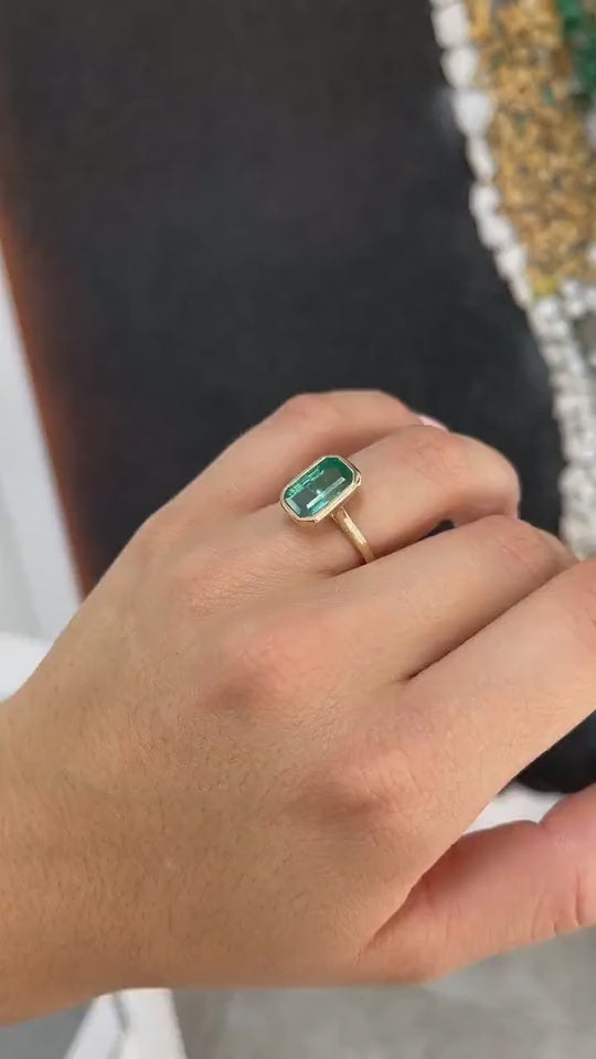 4.76ct elongated emerald-cut natural Colombian emerald solitaire ring in 14K gold with bezel setting, featuring blue-green tone and sleek modern design