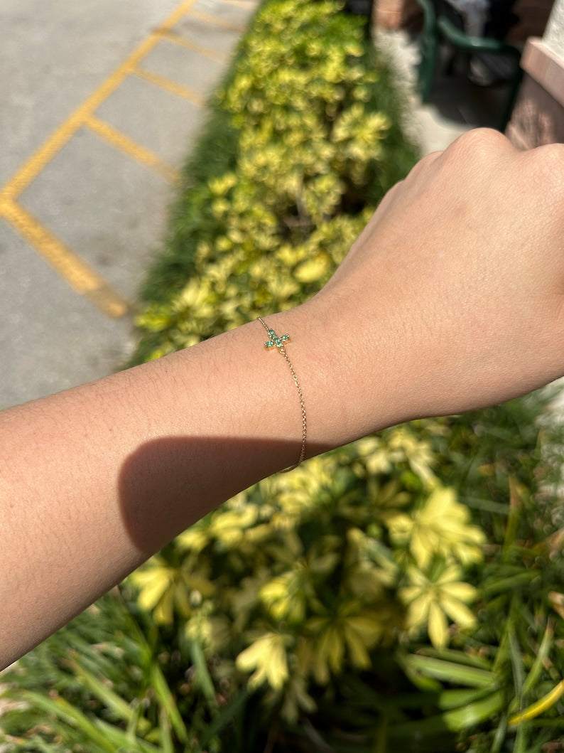 14K gold emerald cross bracelet featuring a 0.20tcw vivid medium green natural emerald and round cut design.