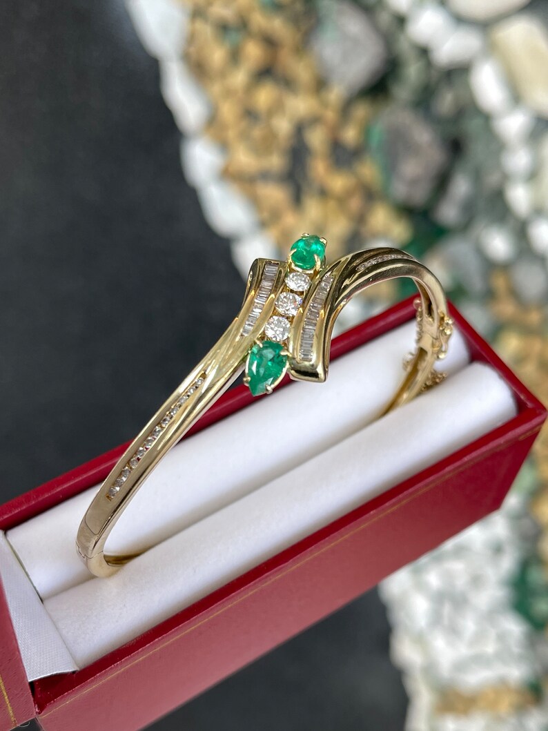Medium yellowish green emerald bangle bracelet with round cut and triple diamond accents in 14K yellow gold, Colombian Emerald brand.