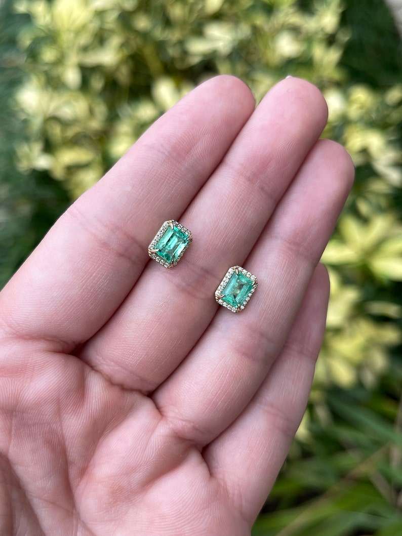 Colombian Emerald 14K gold diamond halo stud earrings featuring 2.10tcw natural emerald-cut diamonds in a classic design.