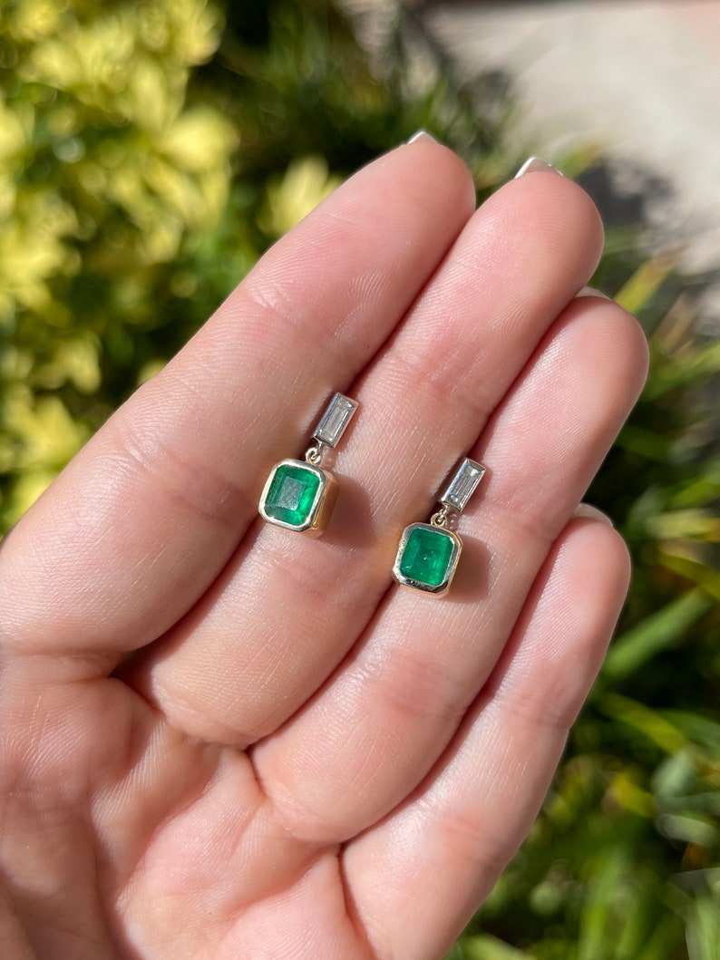 Deep green emerald and diamond bezel earrings in 14K gold featuring 2.30tcw Colombian emeralds and elegant dangle design.