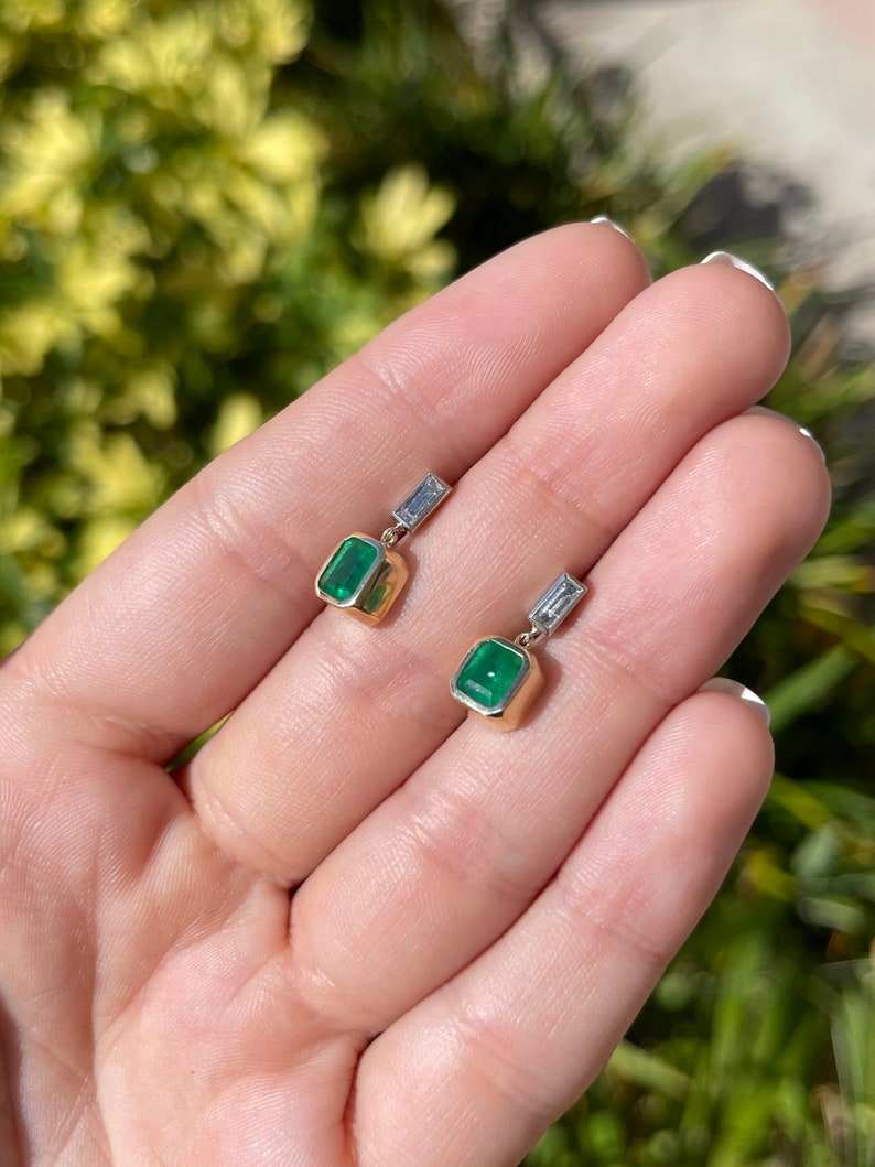 Deep green emerald and diamond bezel dangle earrings in 14K gold, featuring Colombian emeralds and sparkling accents.