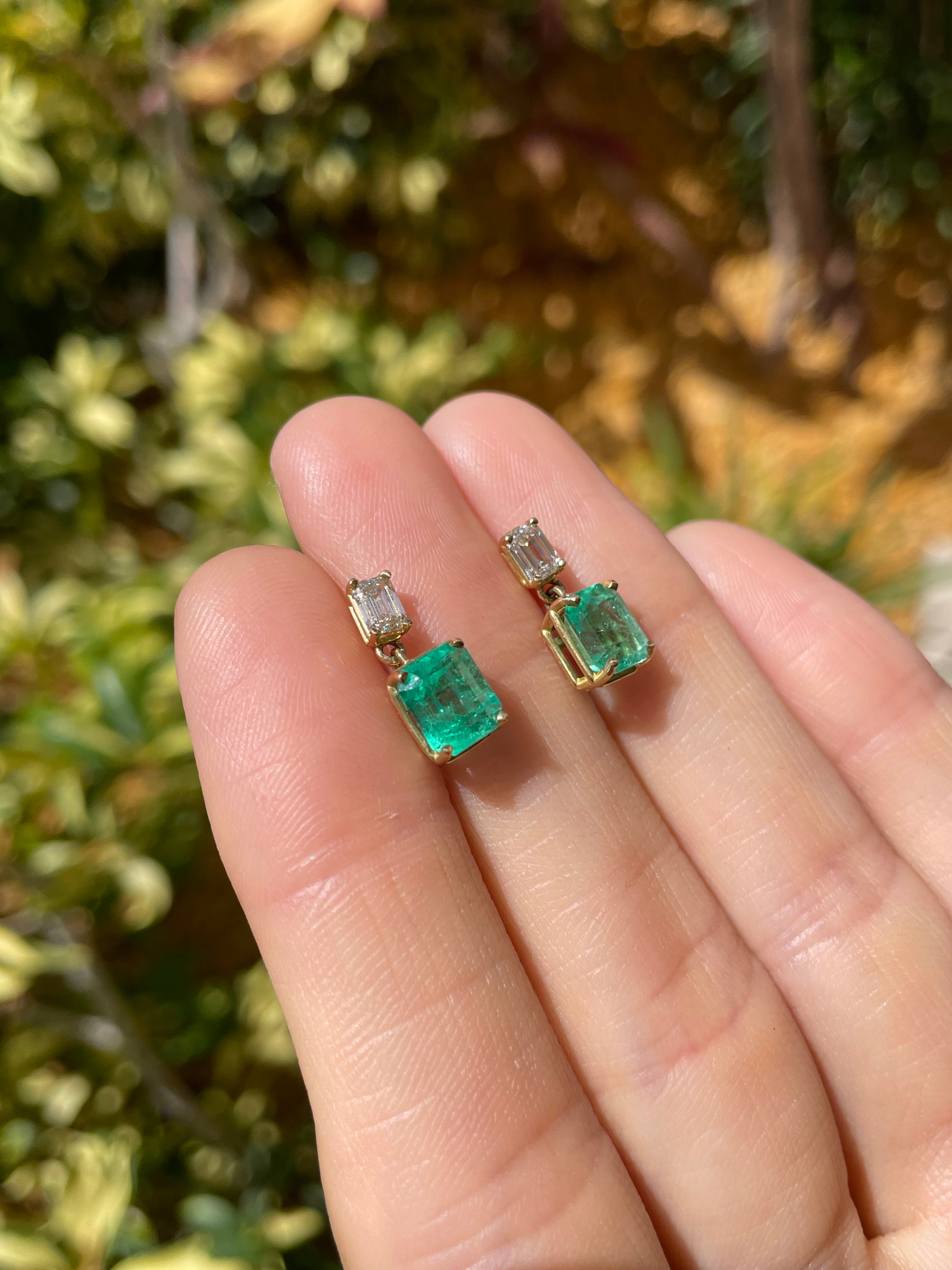 Elongated emerald and diamond dangle earrings with 18K gold setting, featuring natural transparent Colombian emeralds and sparkling diamonds.