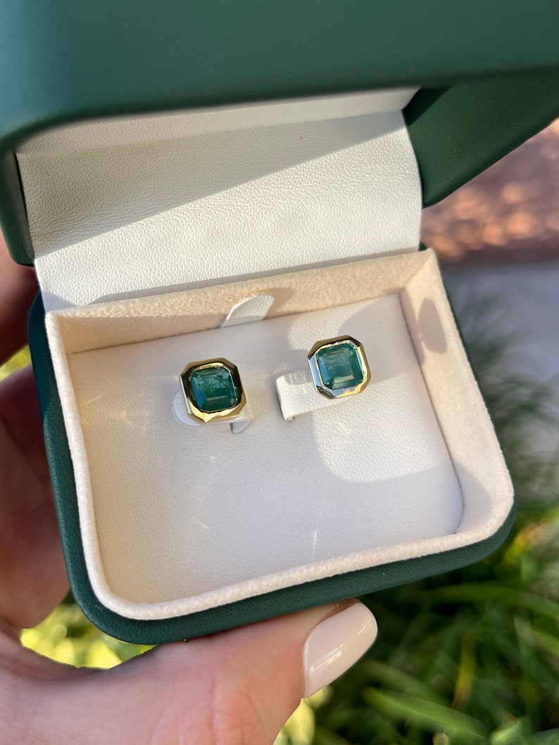Colombian Emerald earrings with dark vivid green top emeralds in 14K yellow gold bezel settings, shown in close-up image.