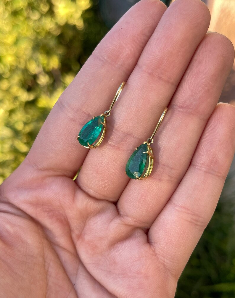 Dark green teardrop emerald earrings with 5.0tcw, 18K gold hooks, Colombian Emerald brand, featuring lush natural emerald dangles.