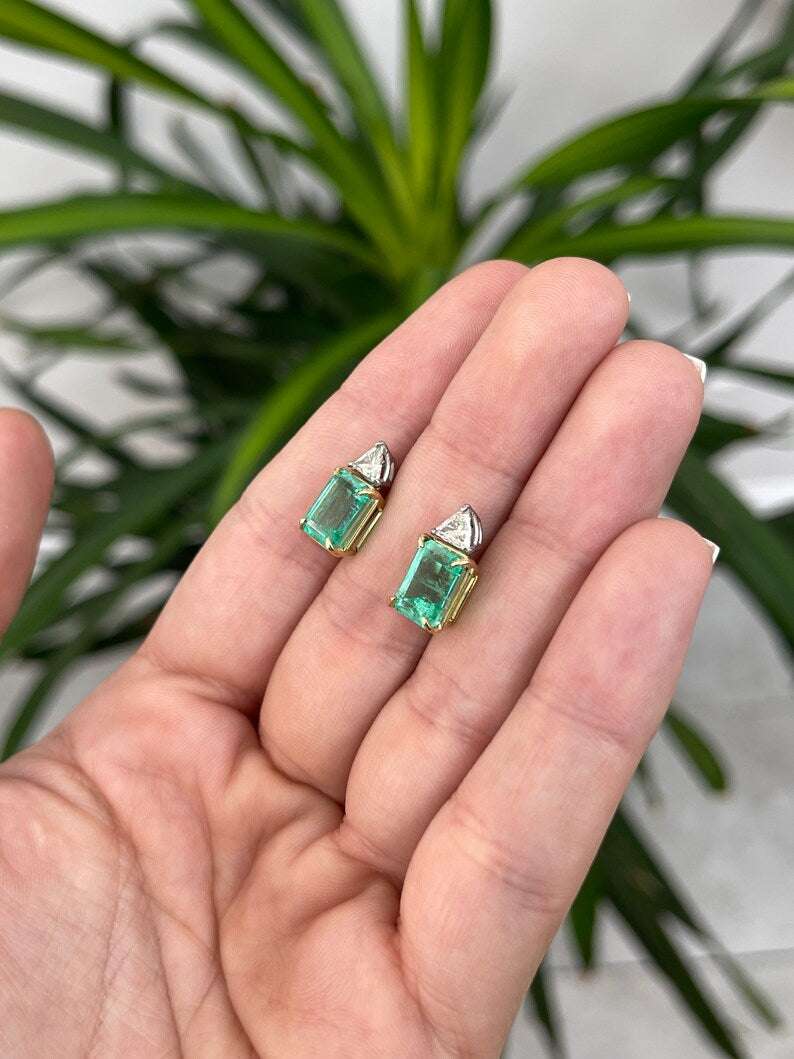 Colombian Emerald brand platinum 18K diamond trillion accent two-stone stud earrings featuring emerald cut green gemstones and sparkling diamonds.