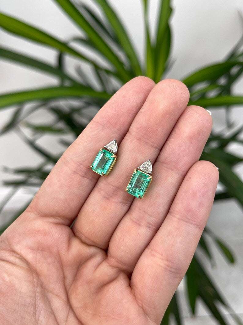 Colombian Emerald brand two-stone platinum earrings with 6.73tcw Colombian emeralds and diamond trillion accents.