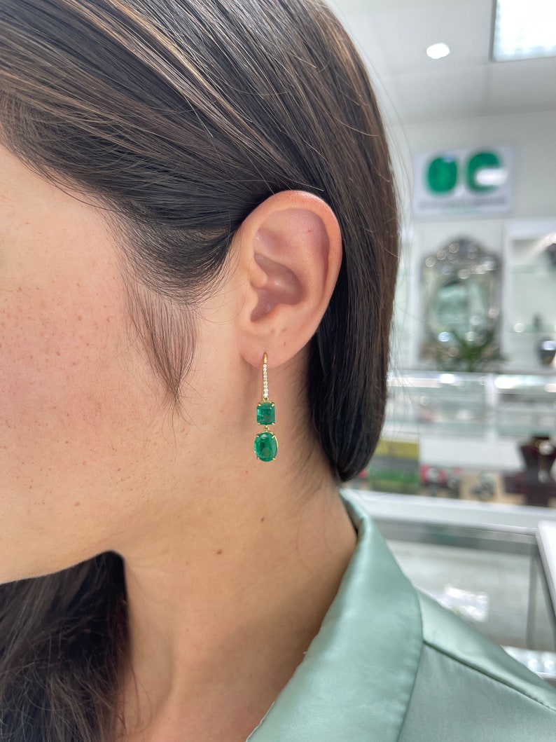 Dark emerald diamond accent dangle earrings in 18K gold, featuring 9.49 carats of natural fine-quality Colombian emeralds.