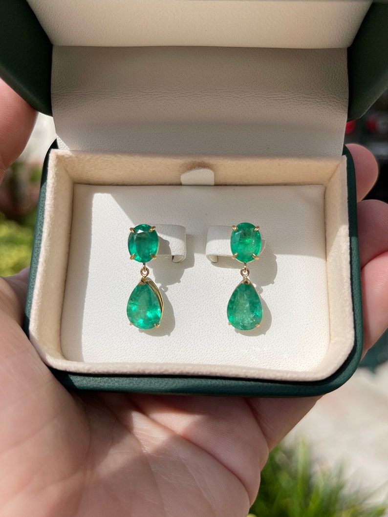 Colombian Emerald earrings with 9.78tcw dark green oval and pear-shaped emerald dangles in 18K gold, showcasing vibrant gemstones.