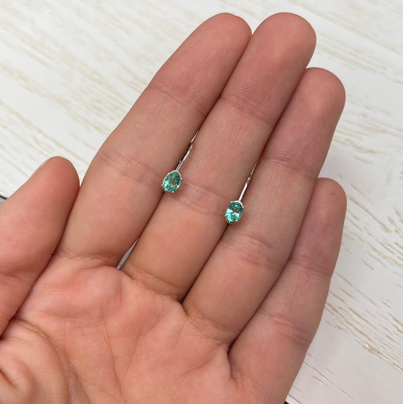Petite Colombian Emerald earrings with 0.50 carats oval cut natural emeralds and 14K gold lever back setting.