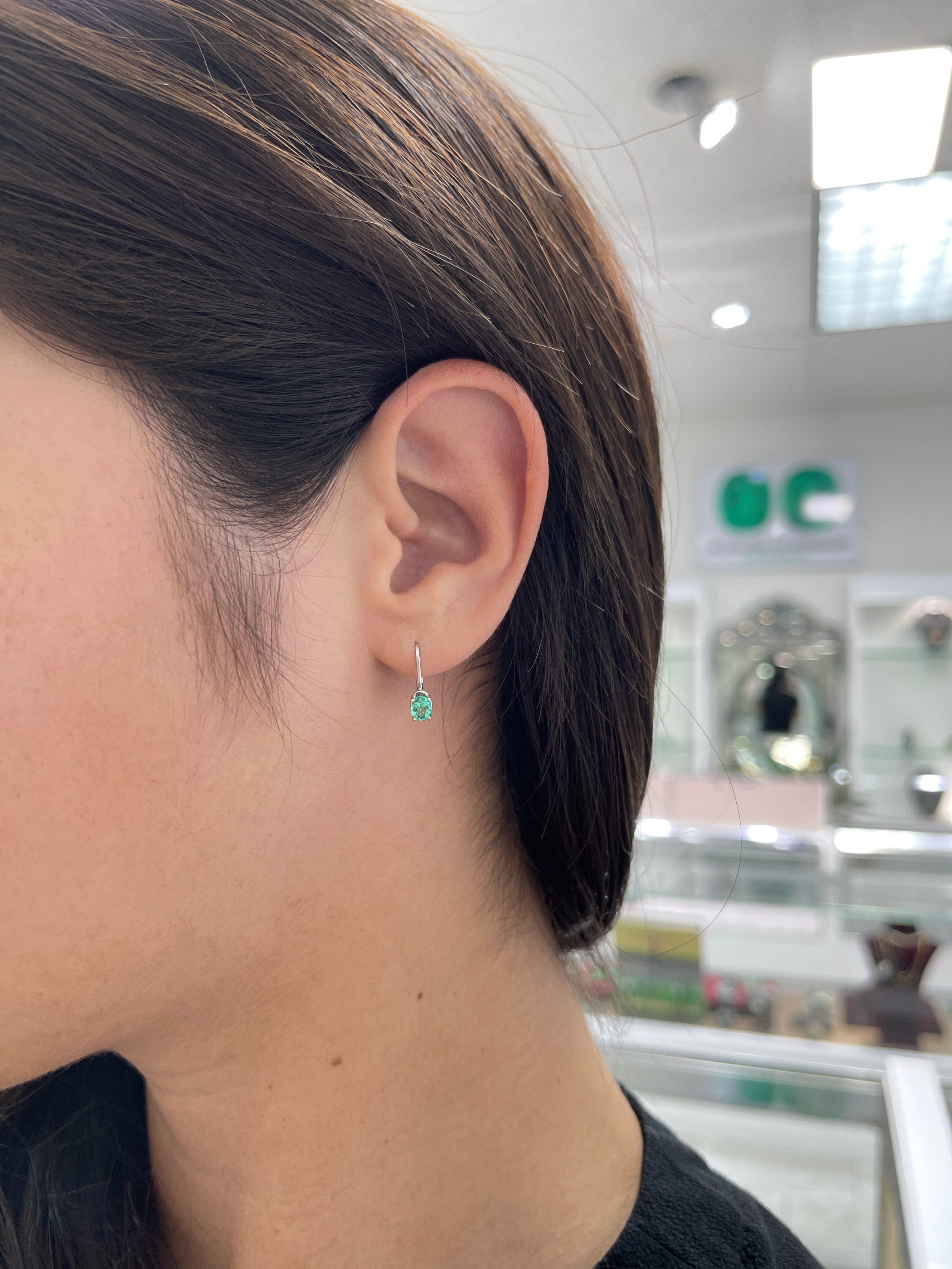 Petite Colombian Emerald earrings with oval cut natural emeralds and 14K lever back setting, showcasing elegant jewelry design.