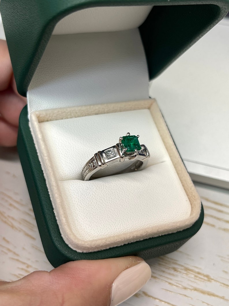 Colombian Emerald 1.20tcw fine quality Asscher and princess cut diamond accent 3-stone engagement ring in 18K gold.