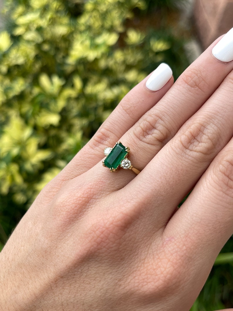 Colombian Emerald 18K gold three-stone engagement ring with deep green emerald and round diamonds, elegant and sparkling jewelry piece