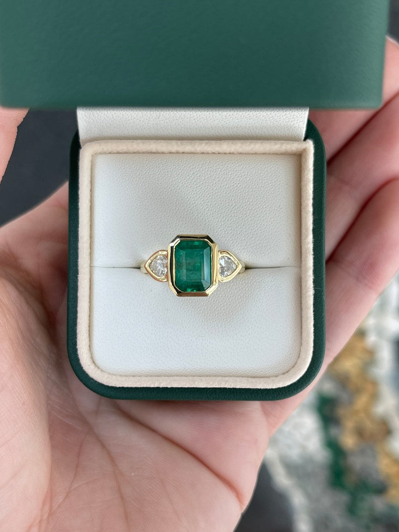 Colombian Emerald 18K yellow gold engagement ring with 2.97tcw emerald and heart-cut diamonds, three-stone design.