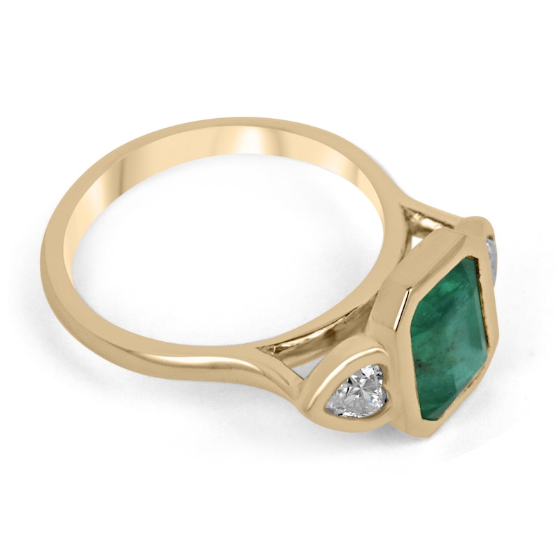 Colombian Emerald 18K yellow gold engagement ring with 2.97tcw emerald and heart-cut diamonds, three-stone design.