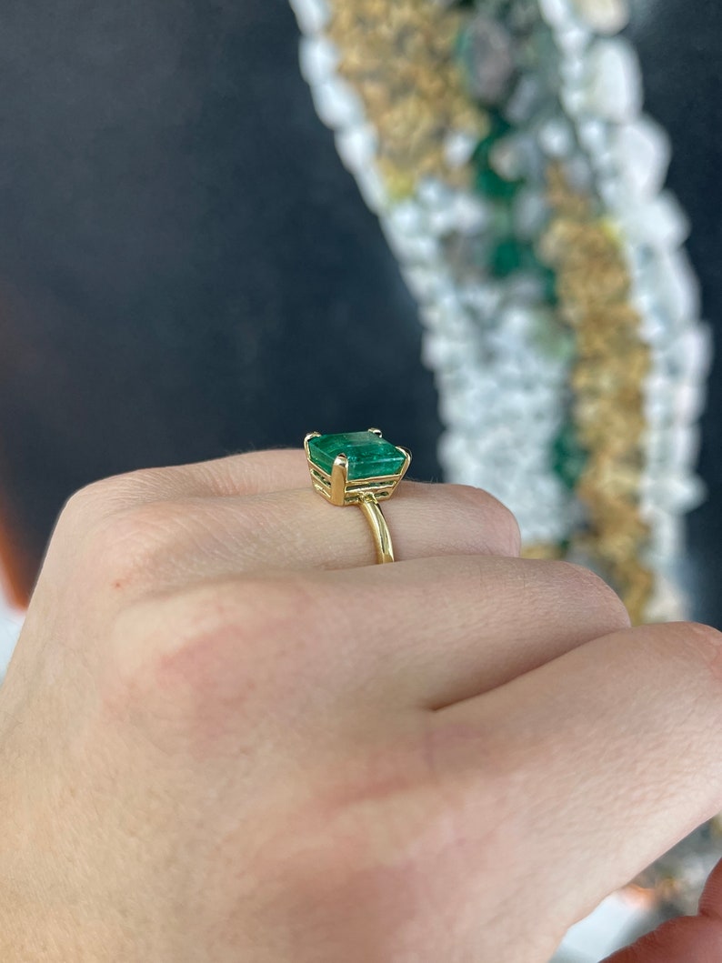 Colombian Emerald 4.10 carat solitaire engagement ring with emerald cut, four prong half bezel setting in 18K yellow gold.